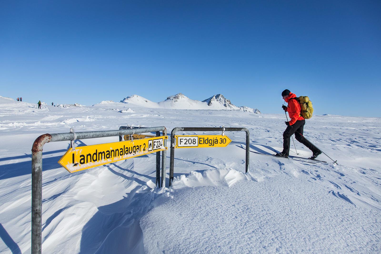 Trekker insnowy plains next to sign pointing towards Landmannalaugar, Eldgjá and Hrauneyjar