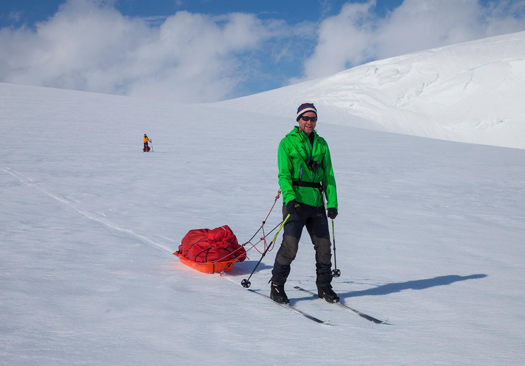A man sliding easily down a slope on the glacier near Mávabyggðir mountain range