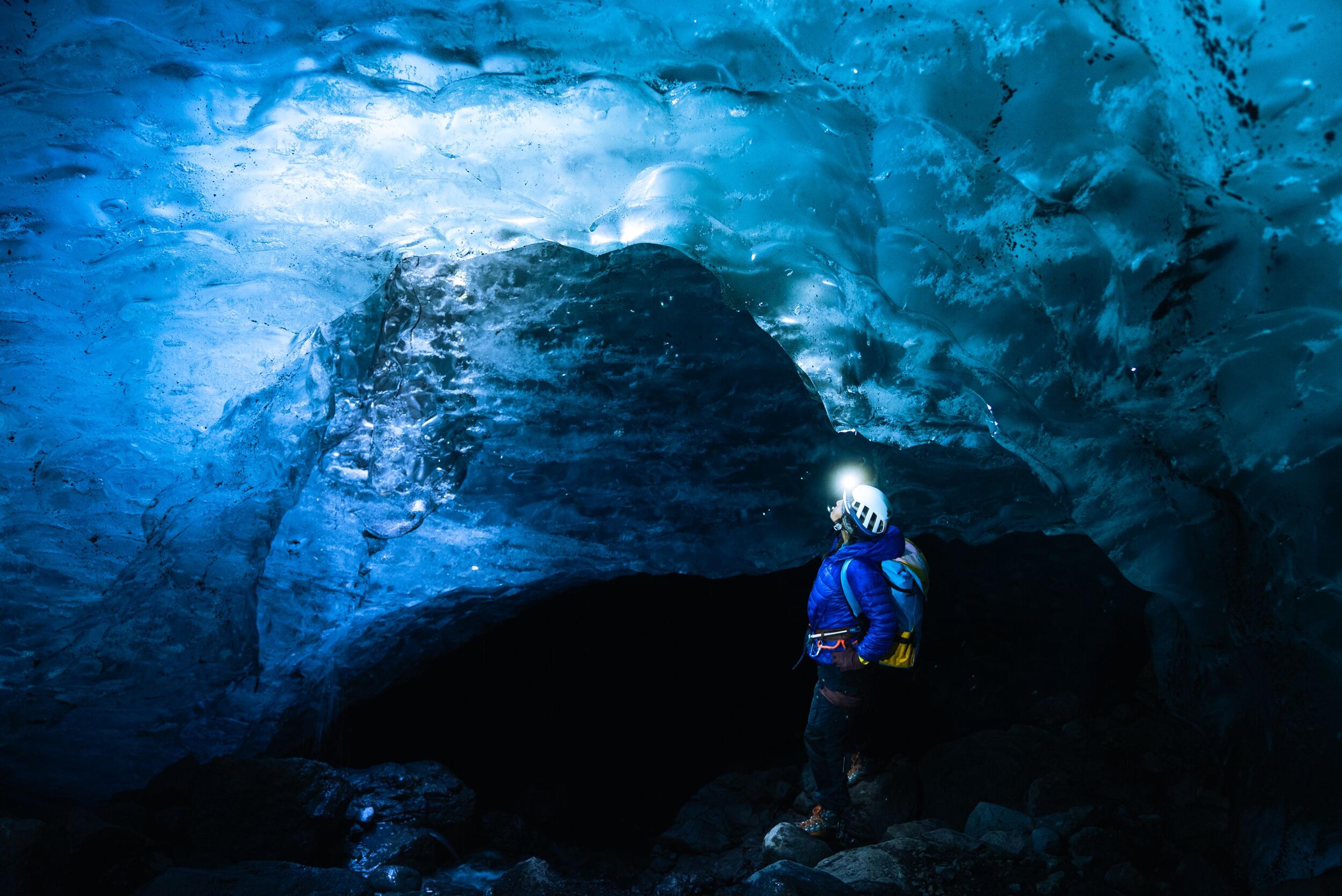 Person standing in an Ice cave with a head light
