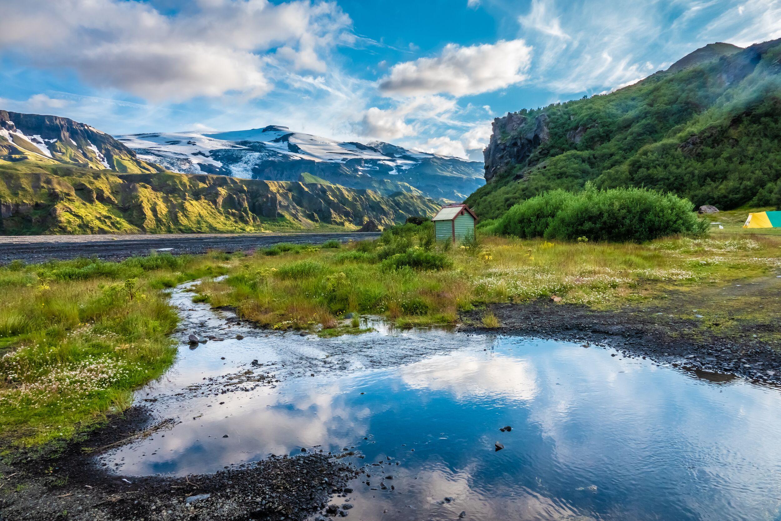 Eyjafjallajökull volcano seen from the green lush oasis of Þórsmörk in the foreground with blue skies above