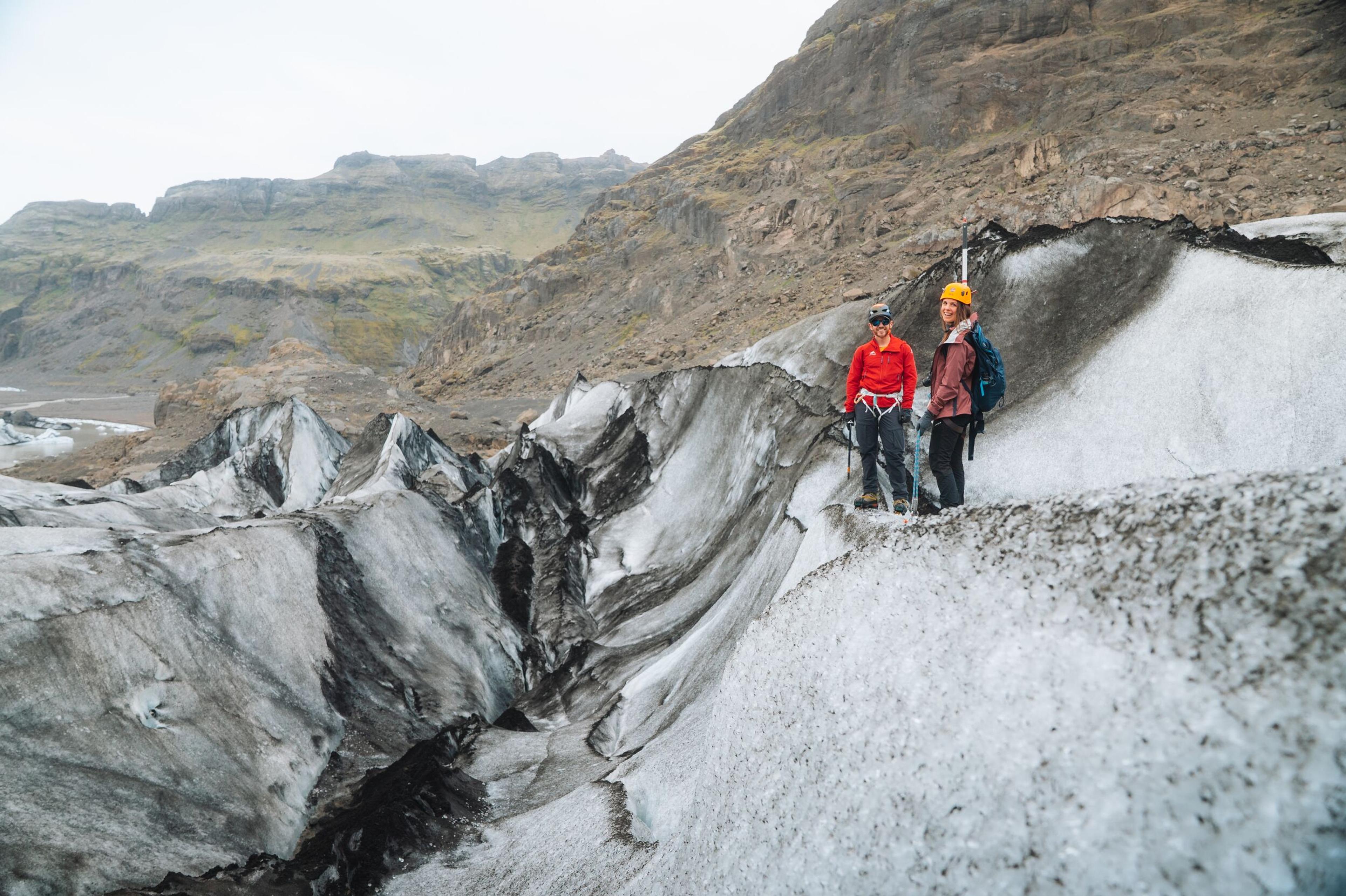 A group of hikers wearing helmets and carrying ice axes carefully explore the rugged terrain of Sólheimajökull glacier. A breathtaking Sólheimajökull glacier hike with views of deep crevasses and volcanic landscapes.
