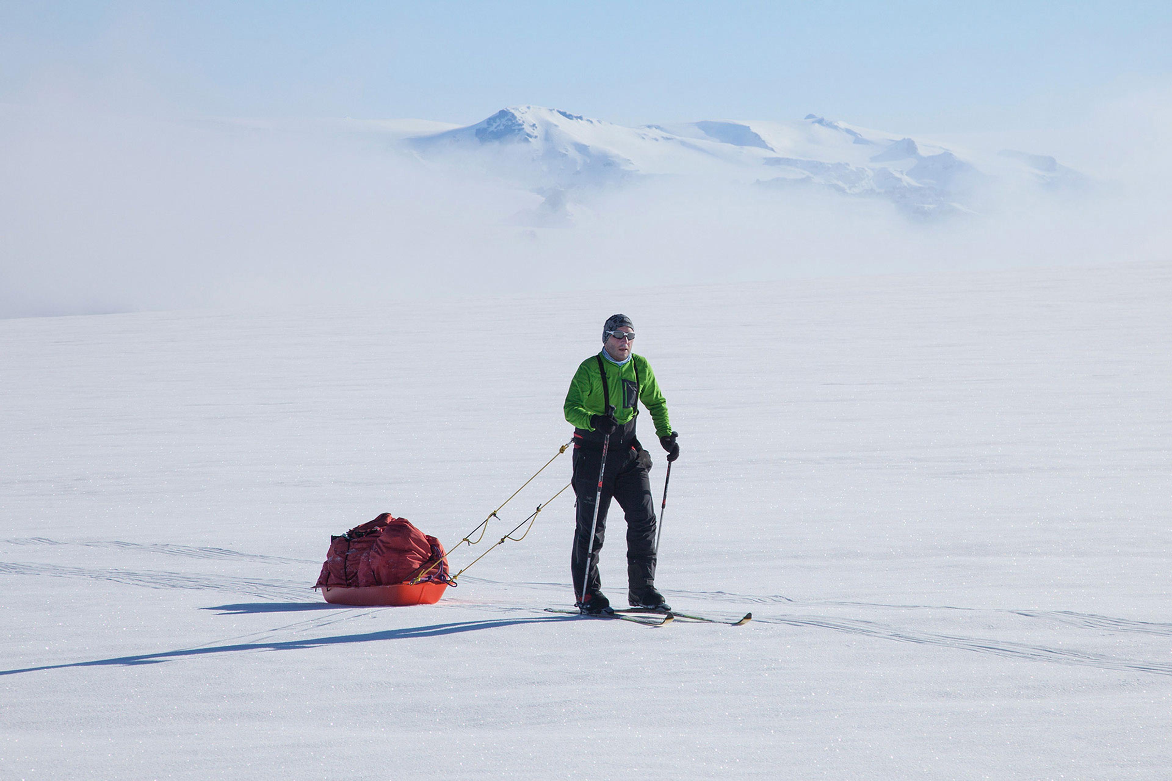 A man on cross country ski hauling a pulka