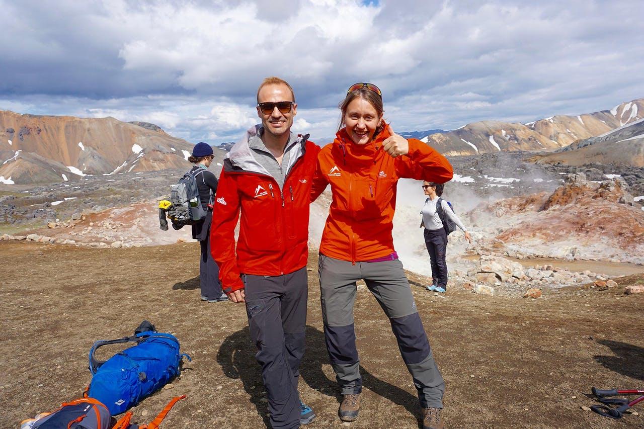 A man and a woman dressed in red smiling for the camera on the Laugavegur trail in Iceland