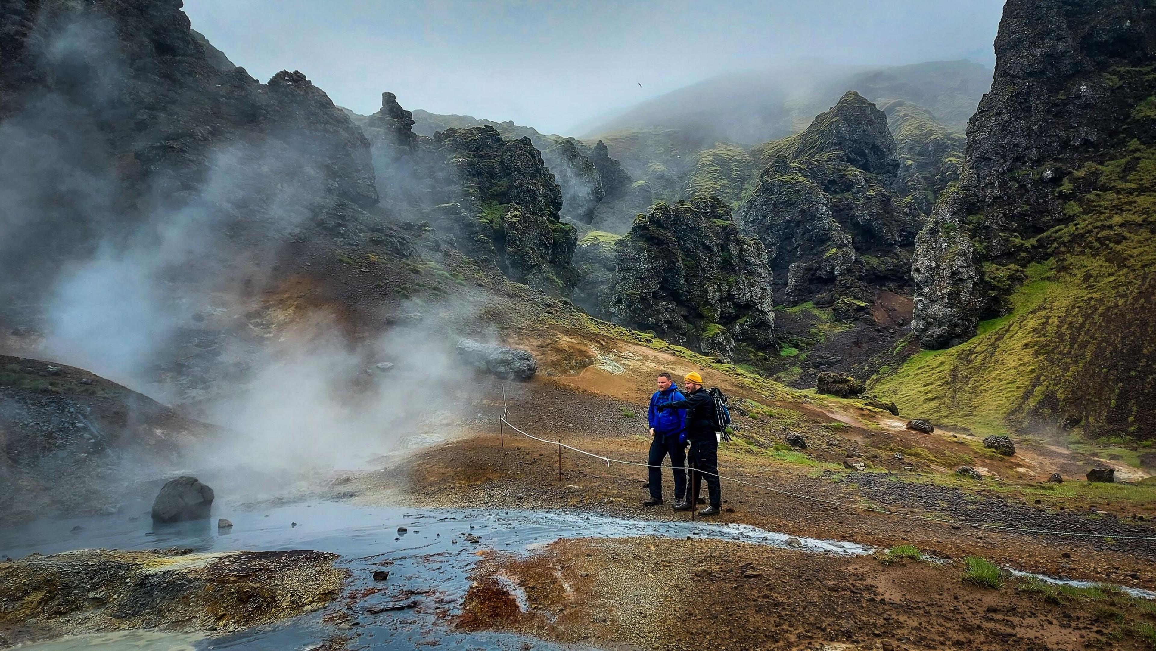 two persons in a rocky terrain with warm water coming from the ground