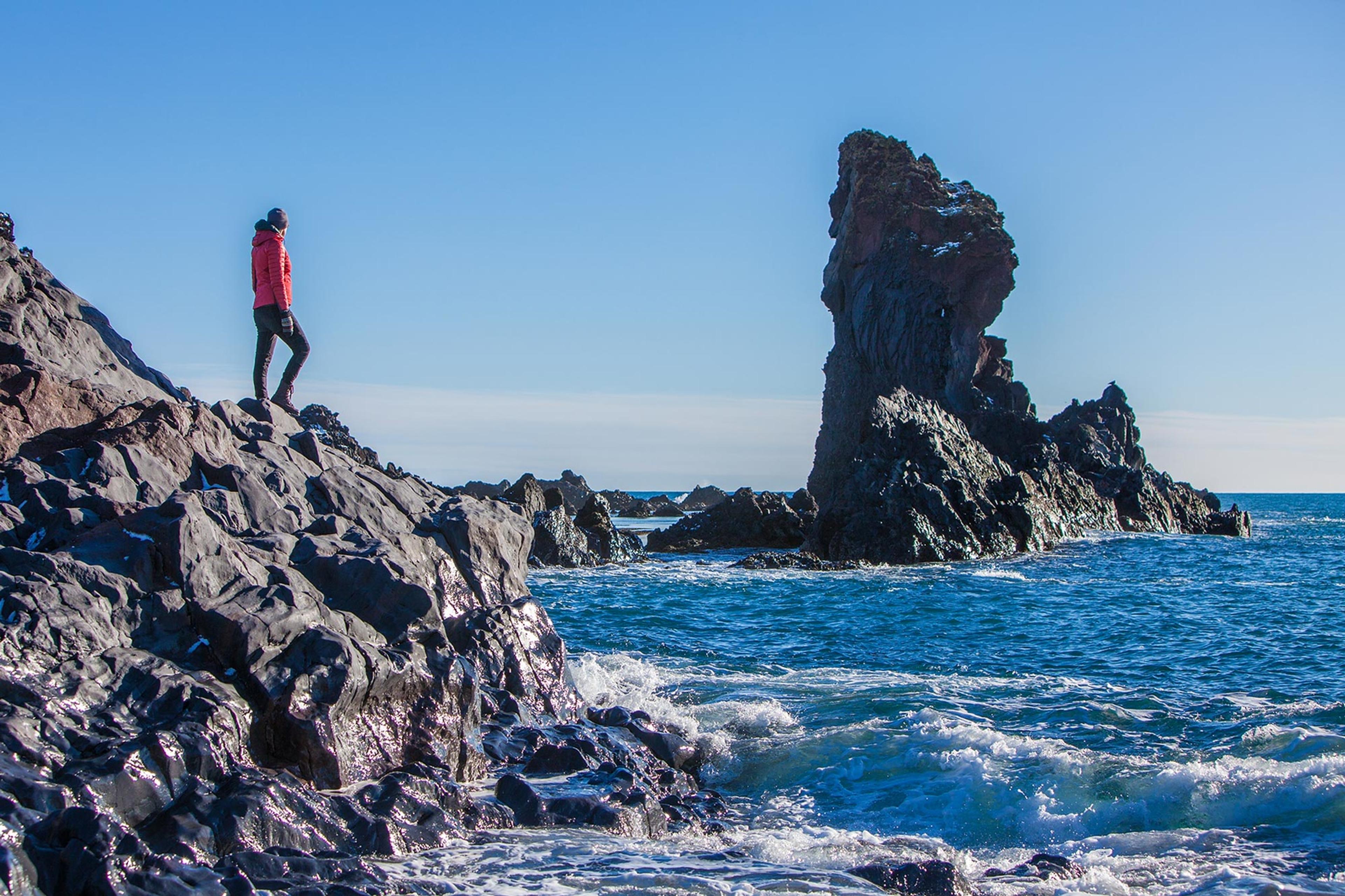 A woman standing on a lava cliff near the sea in Snæfellsnes peninsula western Iceland