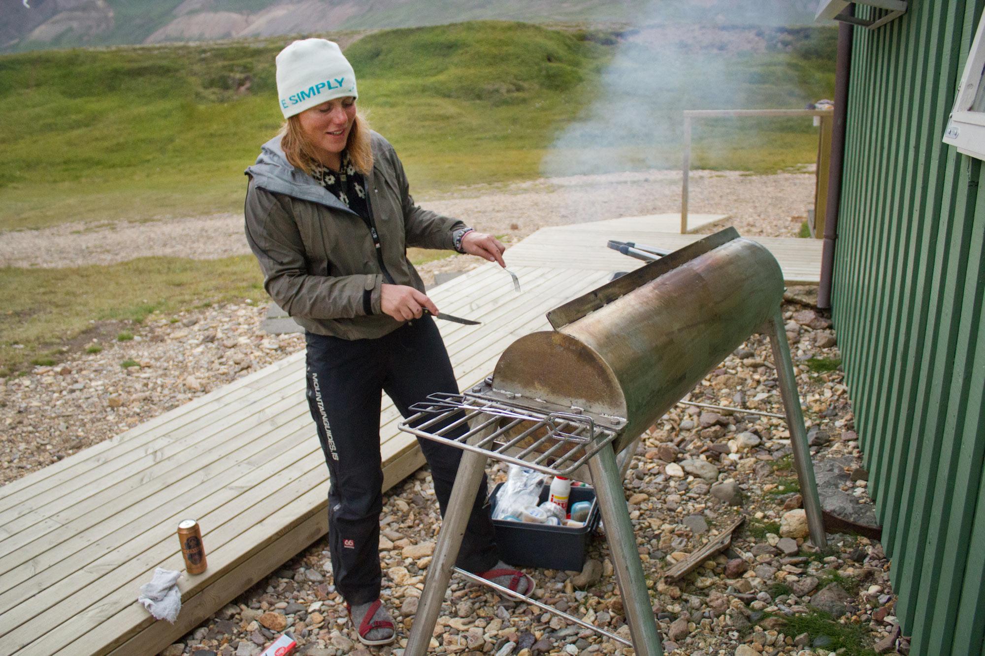 A lady grilling outside a small hut in the east fjords in Iceland