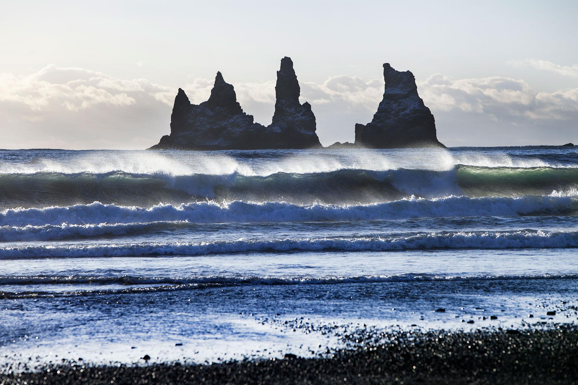 Big waves on a black sand beach in Iceland with gigantic rocks in the ocean