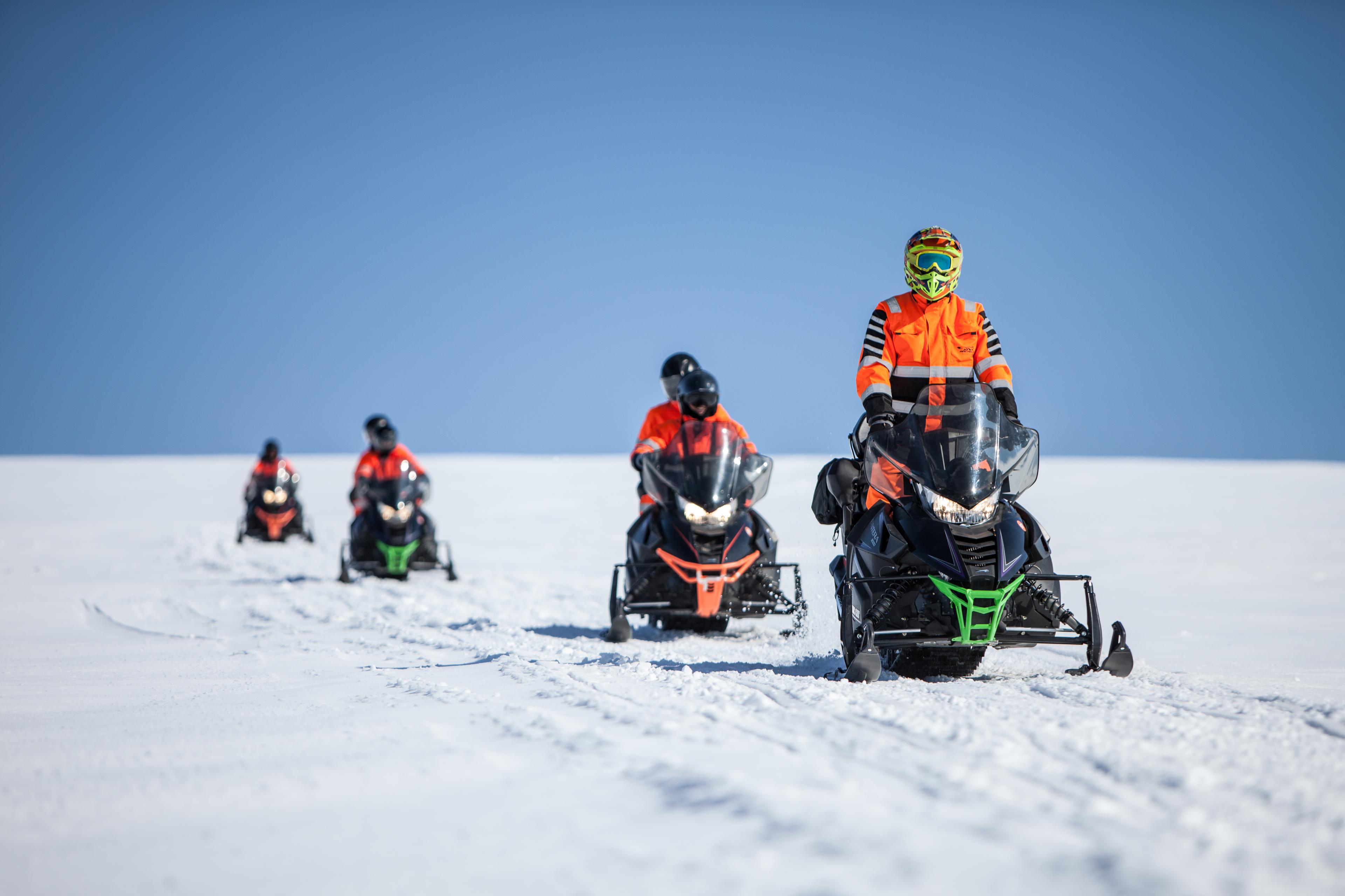 Snowmobile riders crossing the ice cap on a sunny day