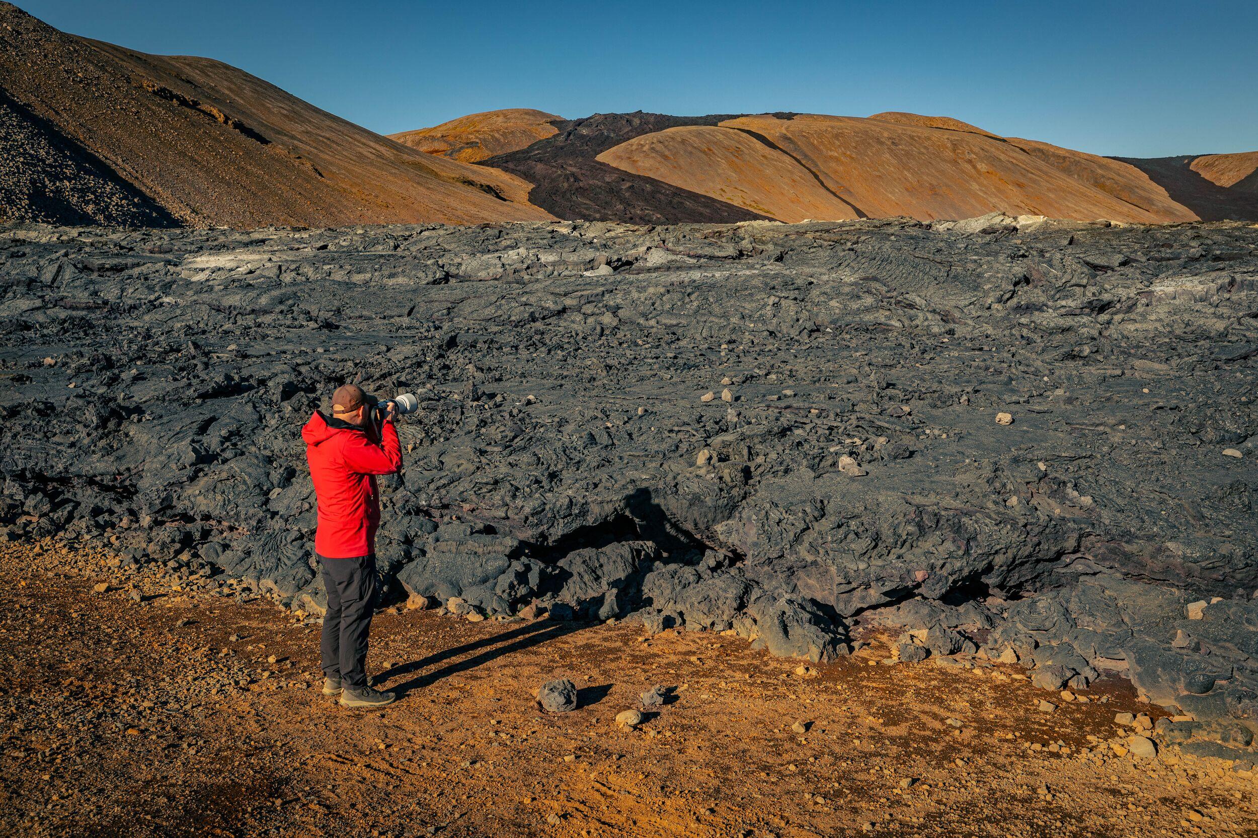 Man photographing Reykjanes volcanic landscape with dark lava fields.