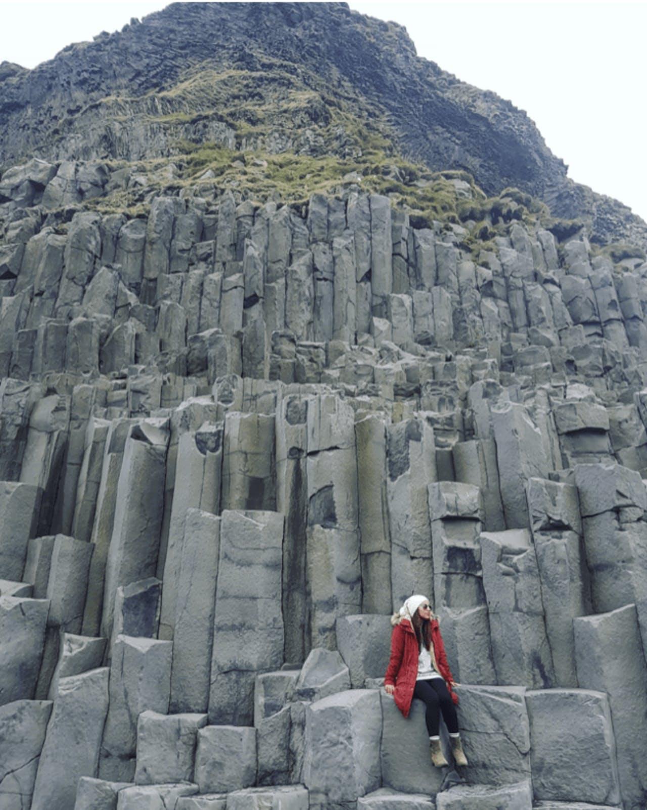 A lady sitting on the Reynisfjara Basalt Columns