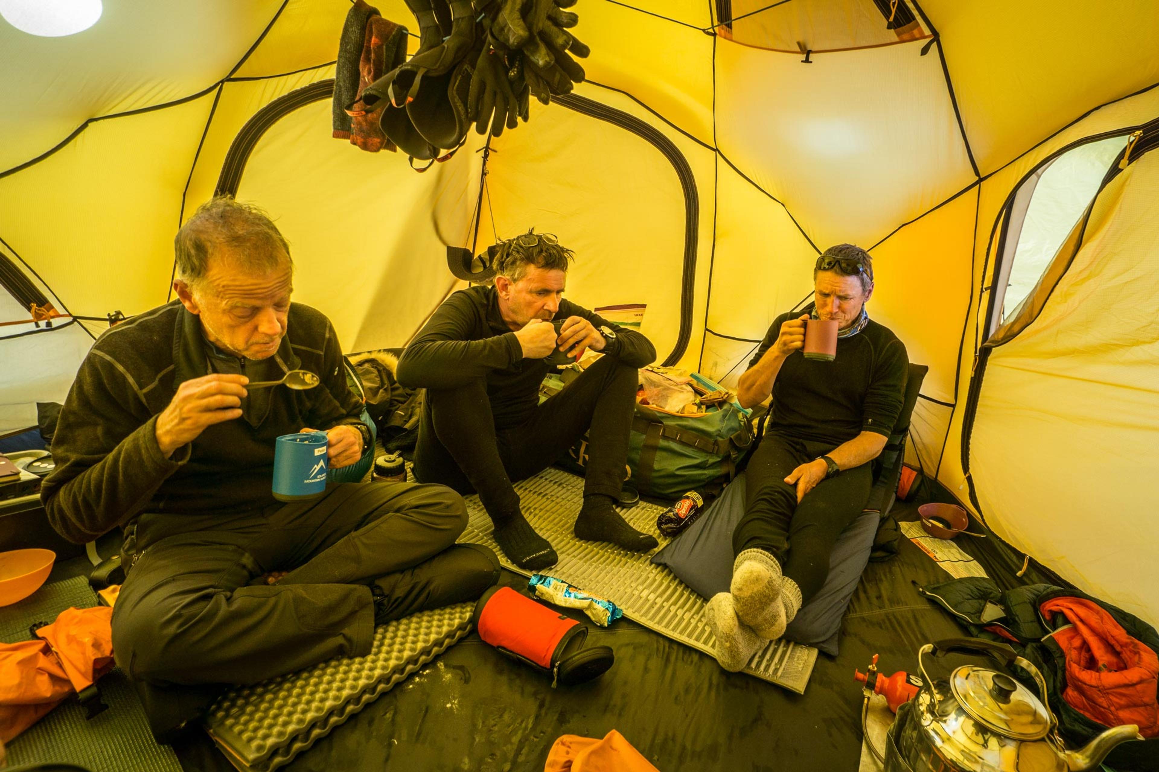 Team members having dinner inside the base camp tent