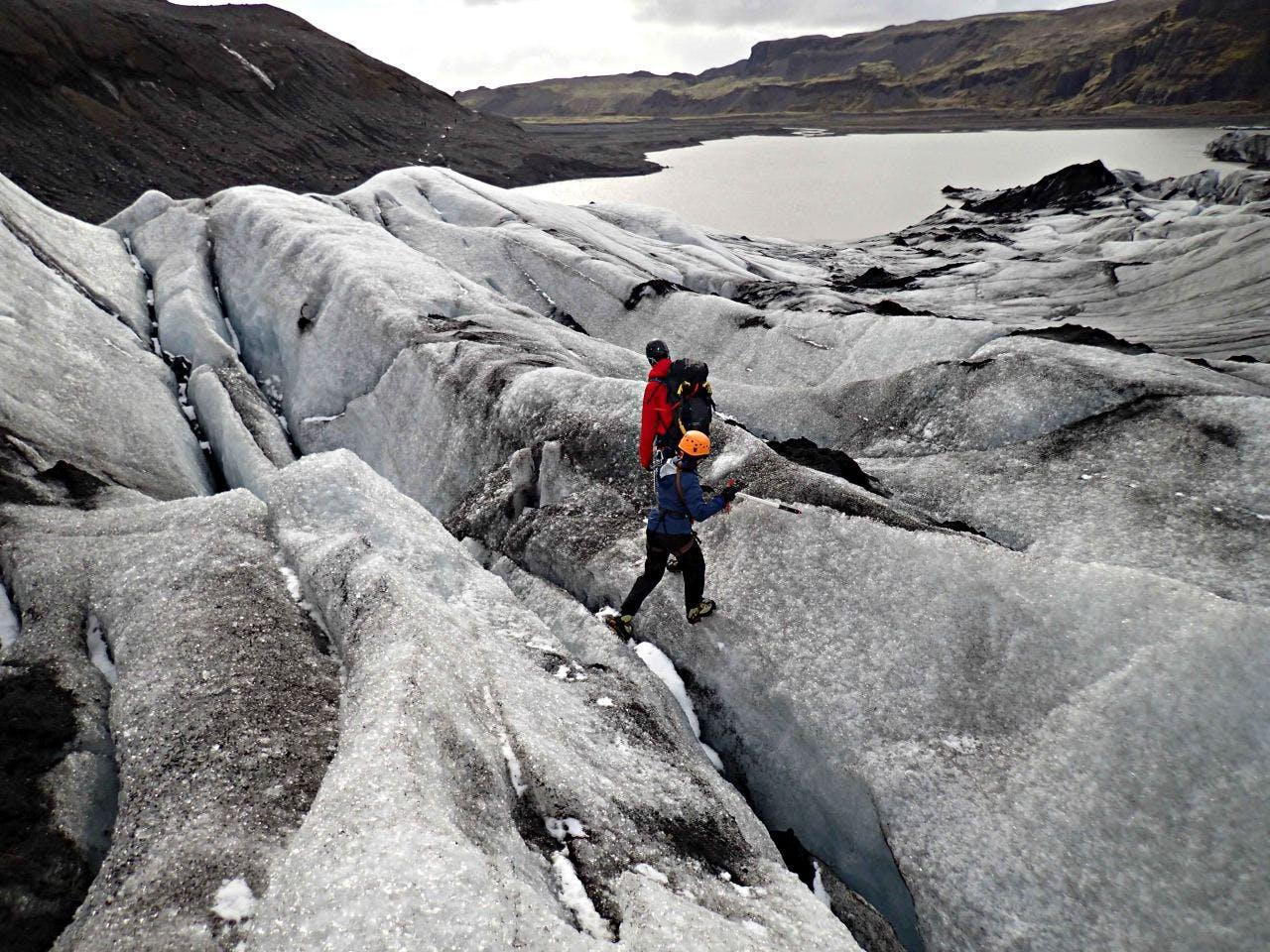 man walking on glacier and black sand