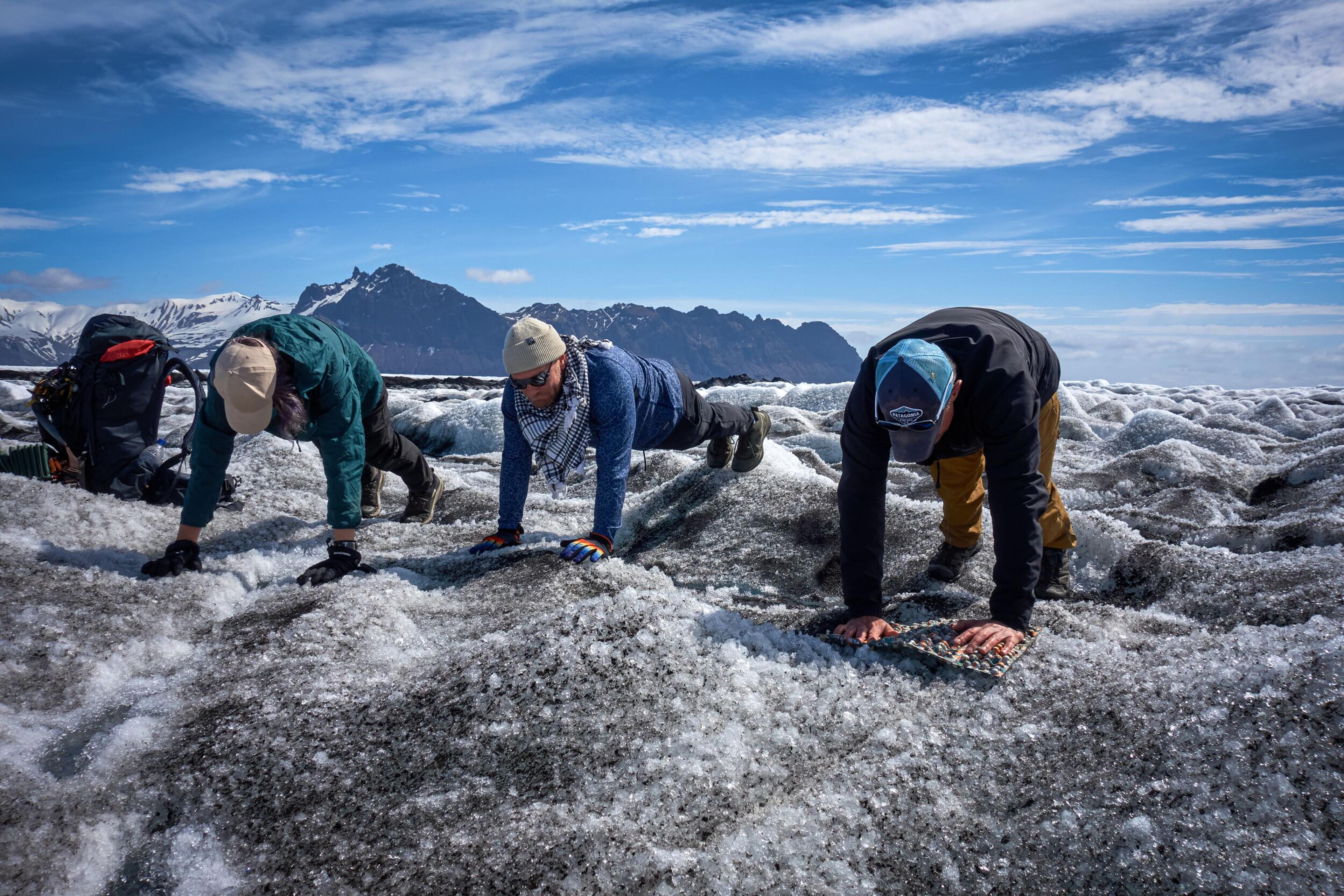 Three people doing a plank on a glacier