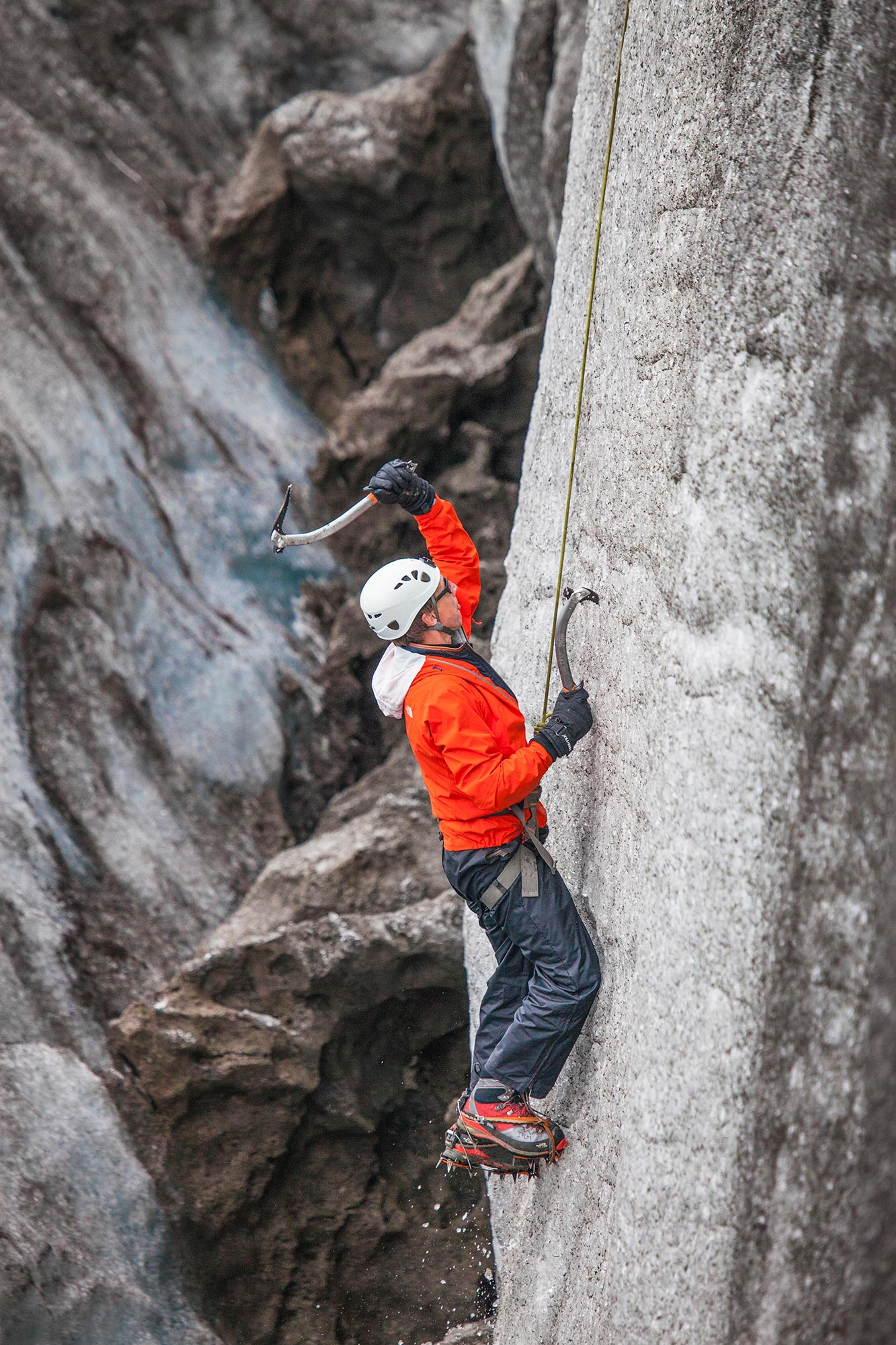 Two climbers tackle an icy ridge in Skaftafell, with one scaling a steep face while the other waits at the top.