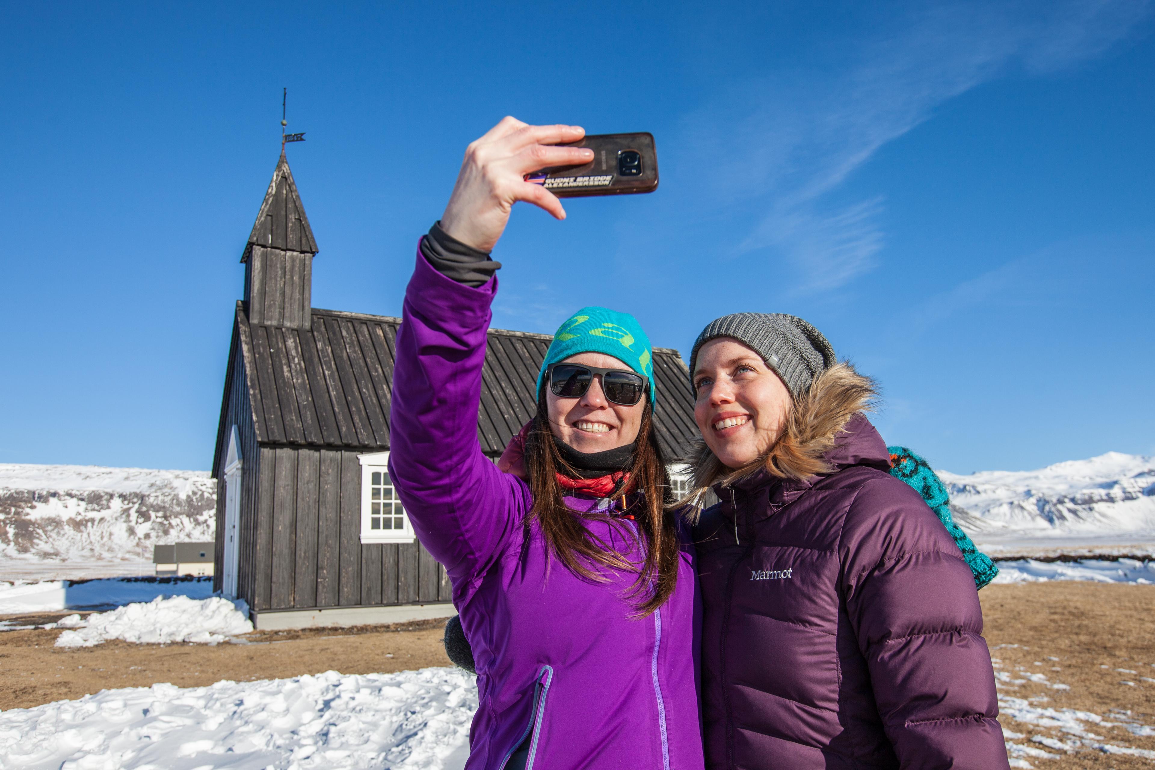 Girls taking a selfie in by Búðakrikja church