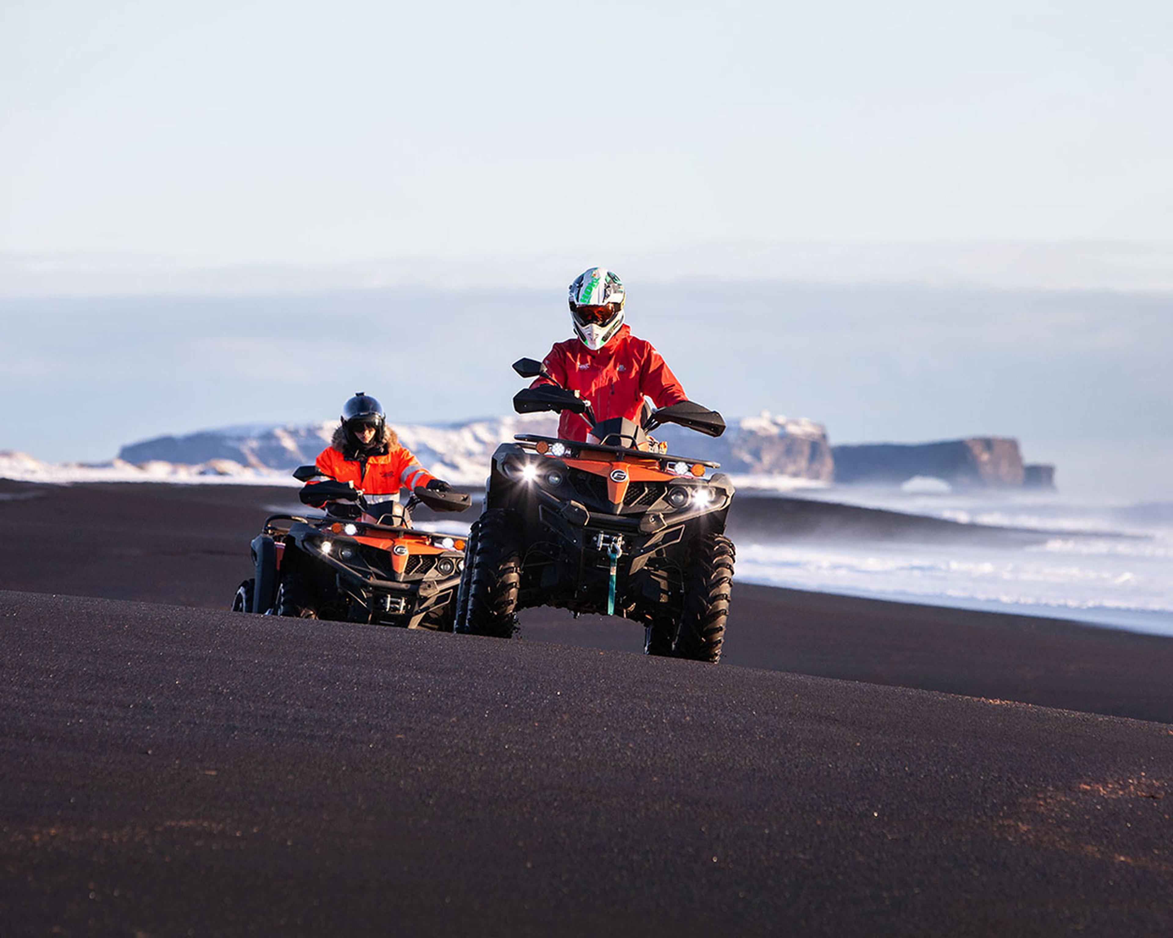 Riding on quad bikes on the black sand breach by Sólheimasandur