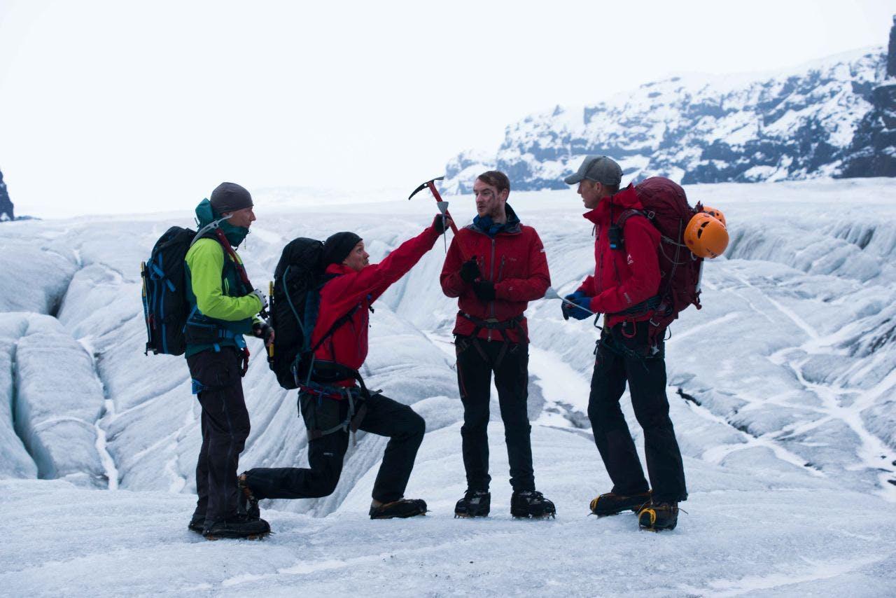 four people standing on a glacier