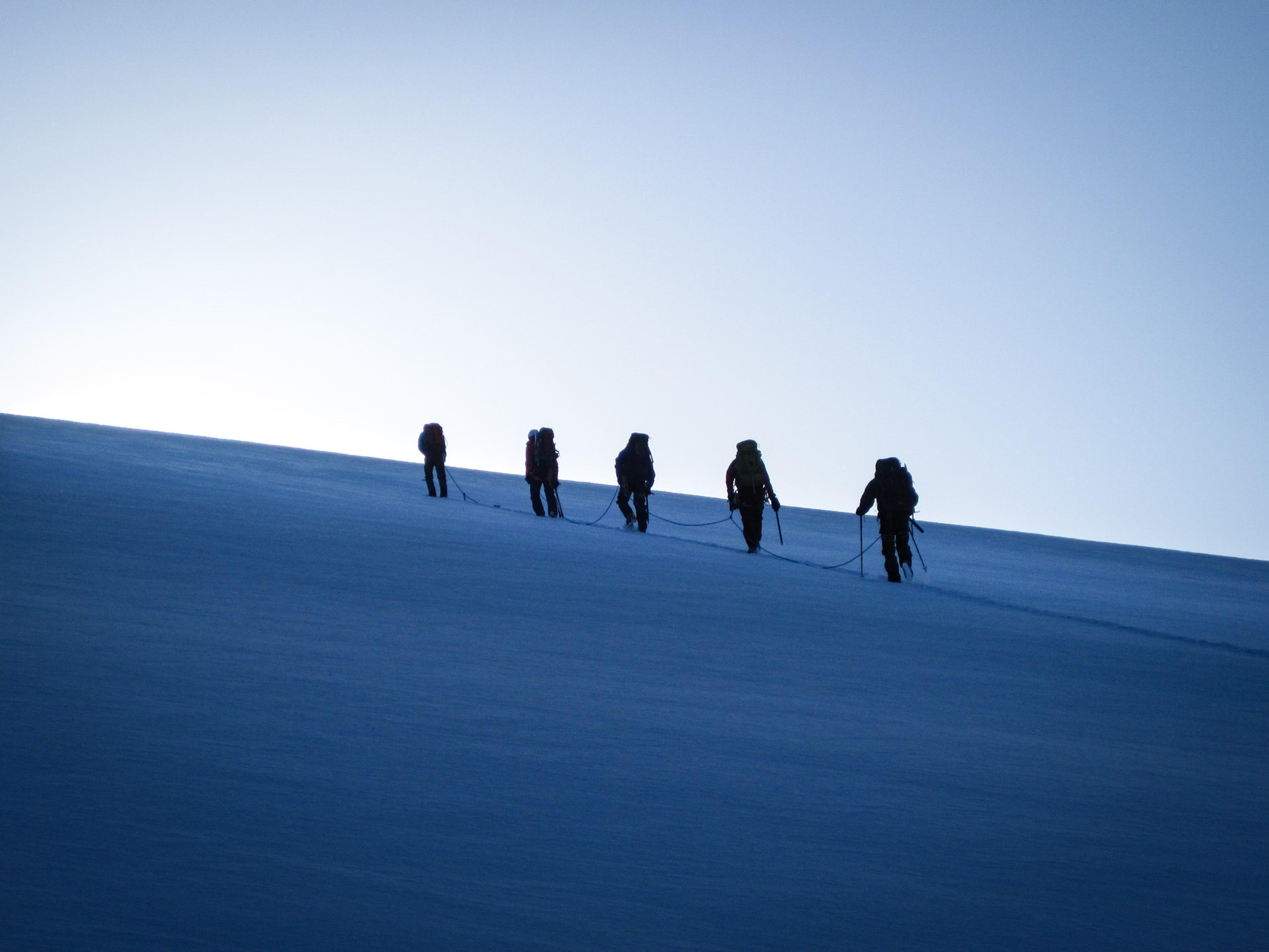 people hiking up a snowy mountain in the morning