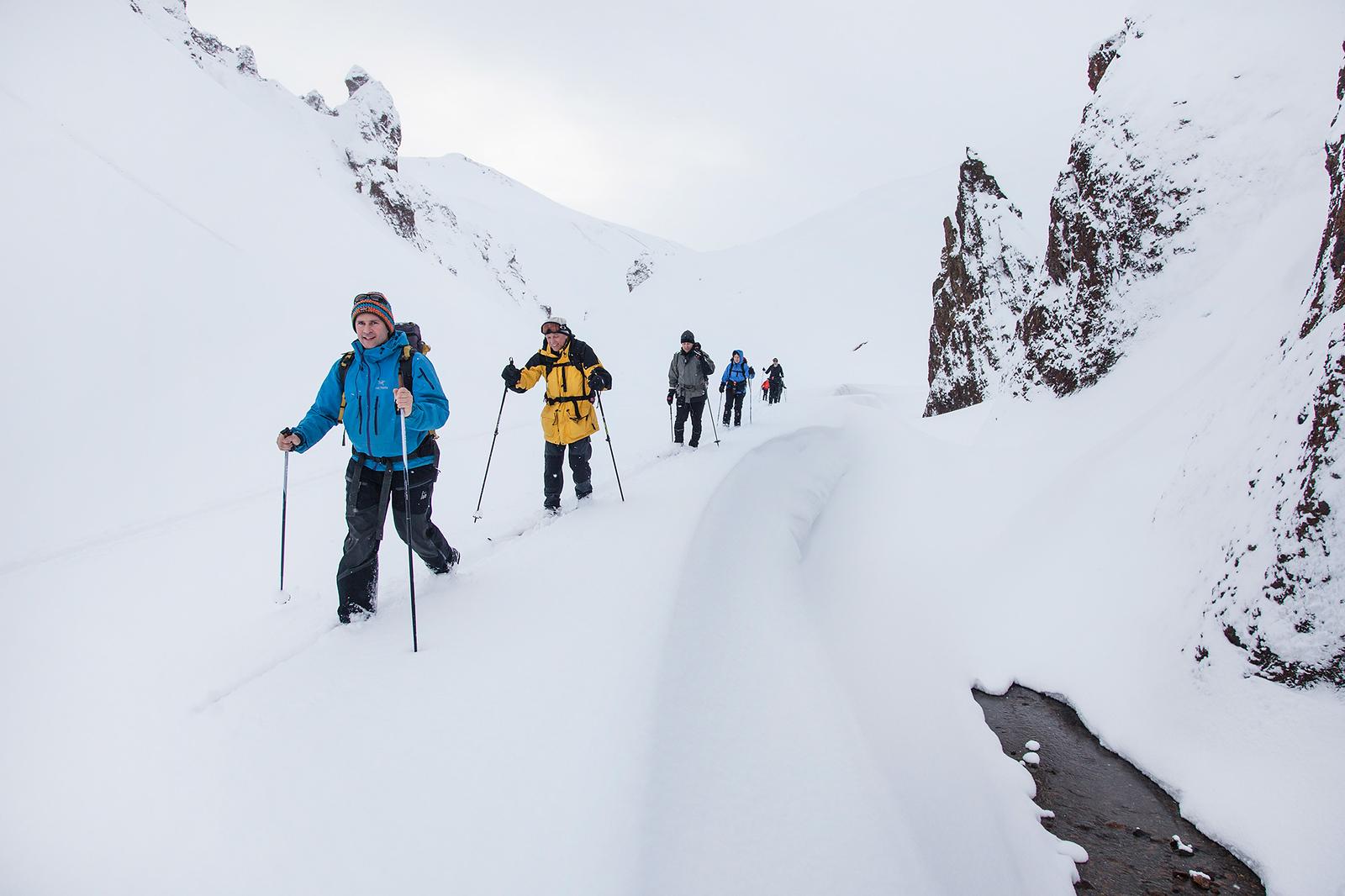 People hiking surrounded by mountains covered in snow