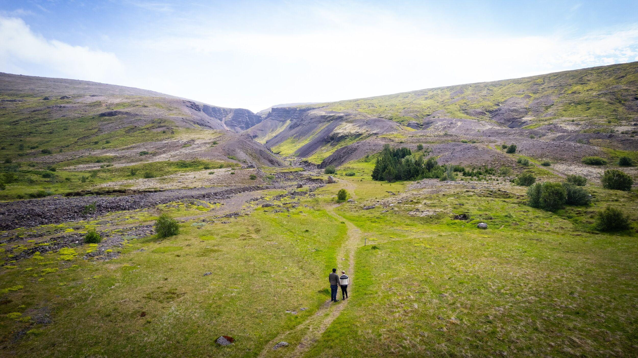 Two people stood on a road in the green oasis of Húsafell