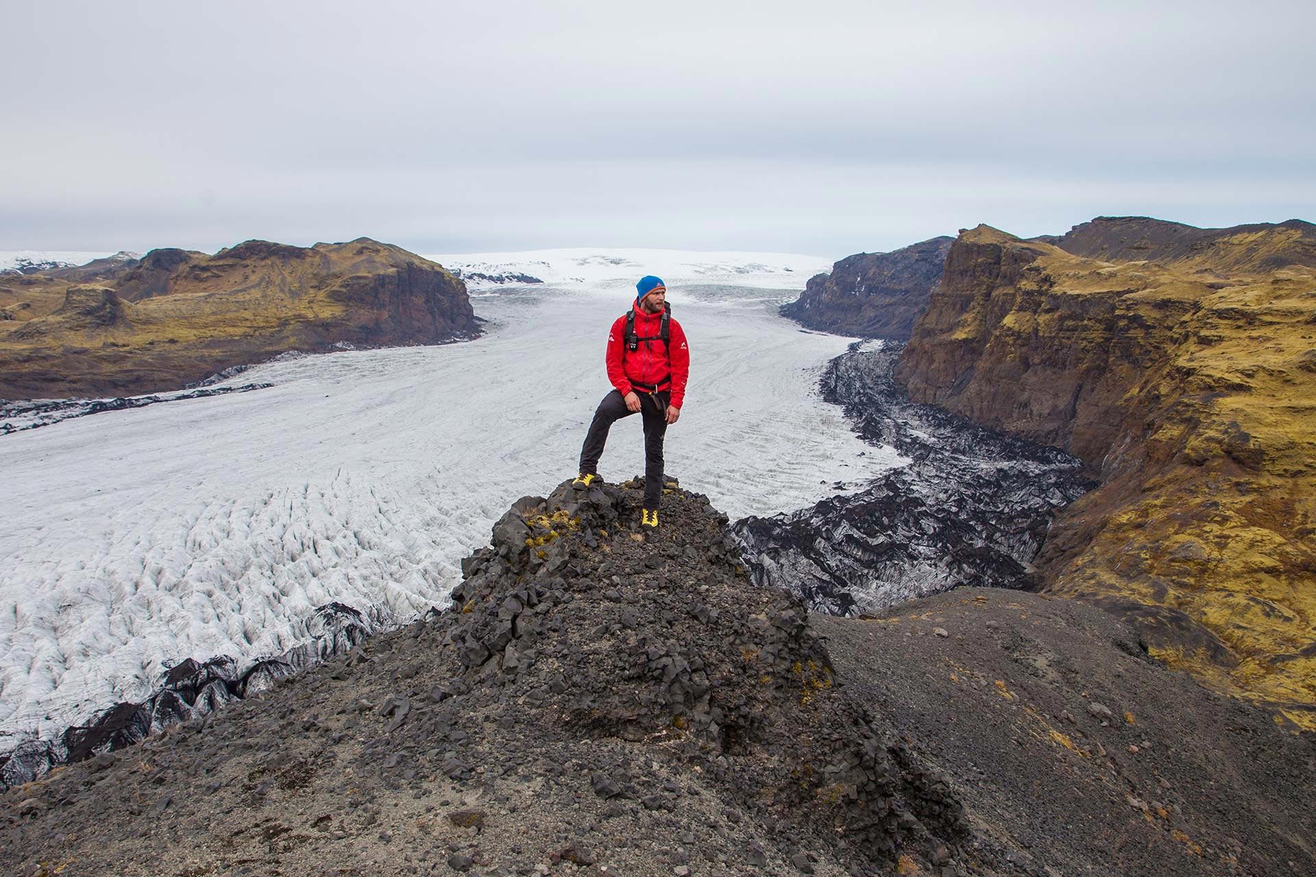 Man in red standing above Solheimajokull glacier in Iceland