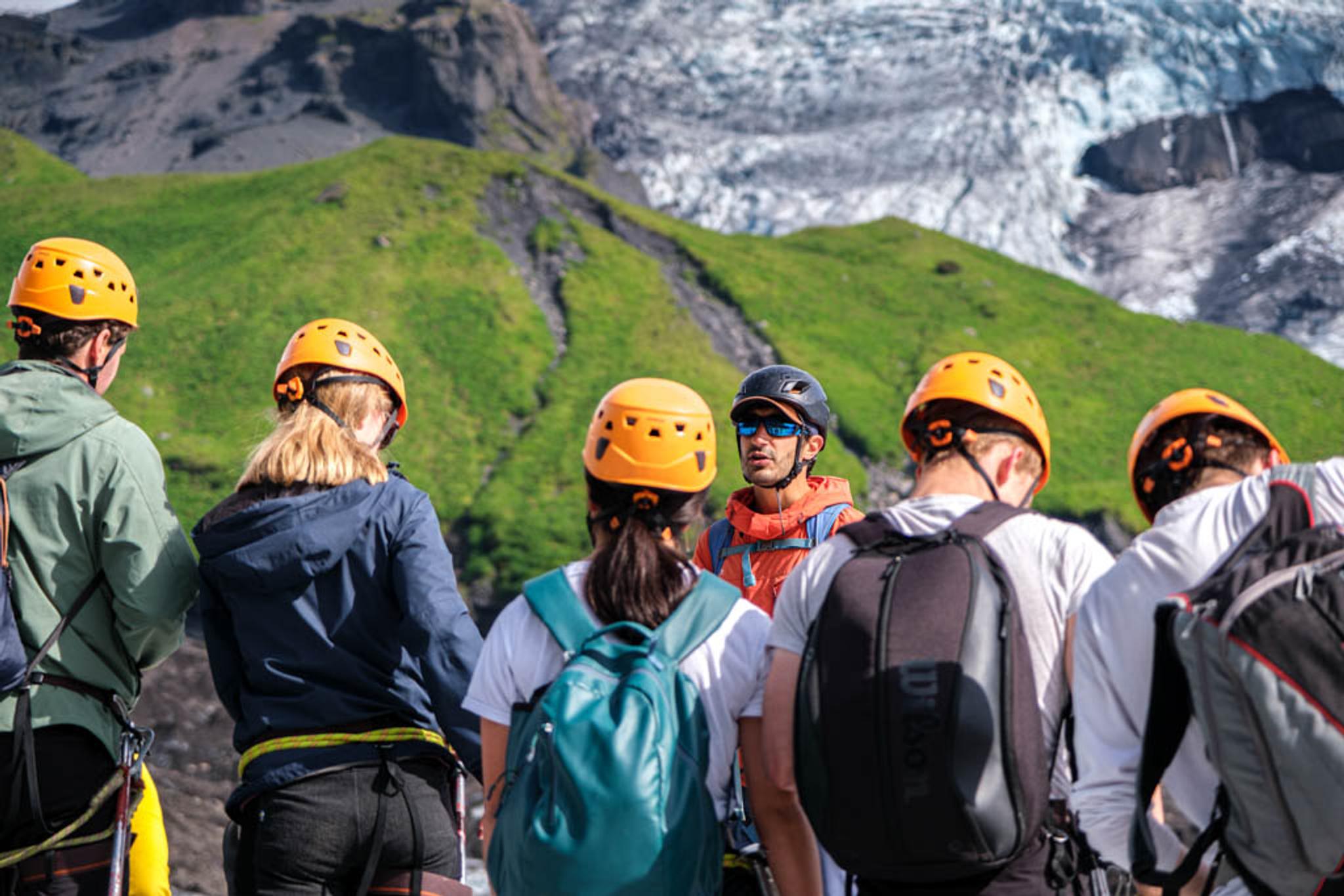 A group of people wearing helmets are listening to the guide's safety briefing