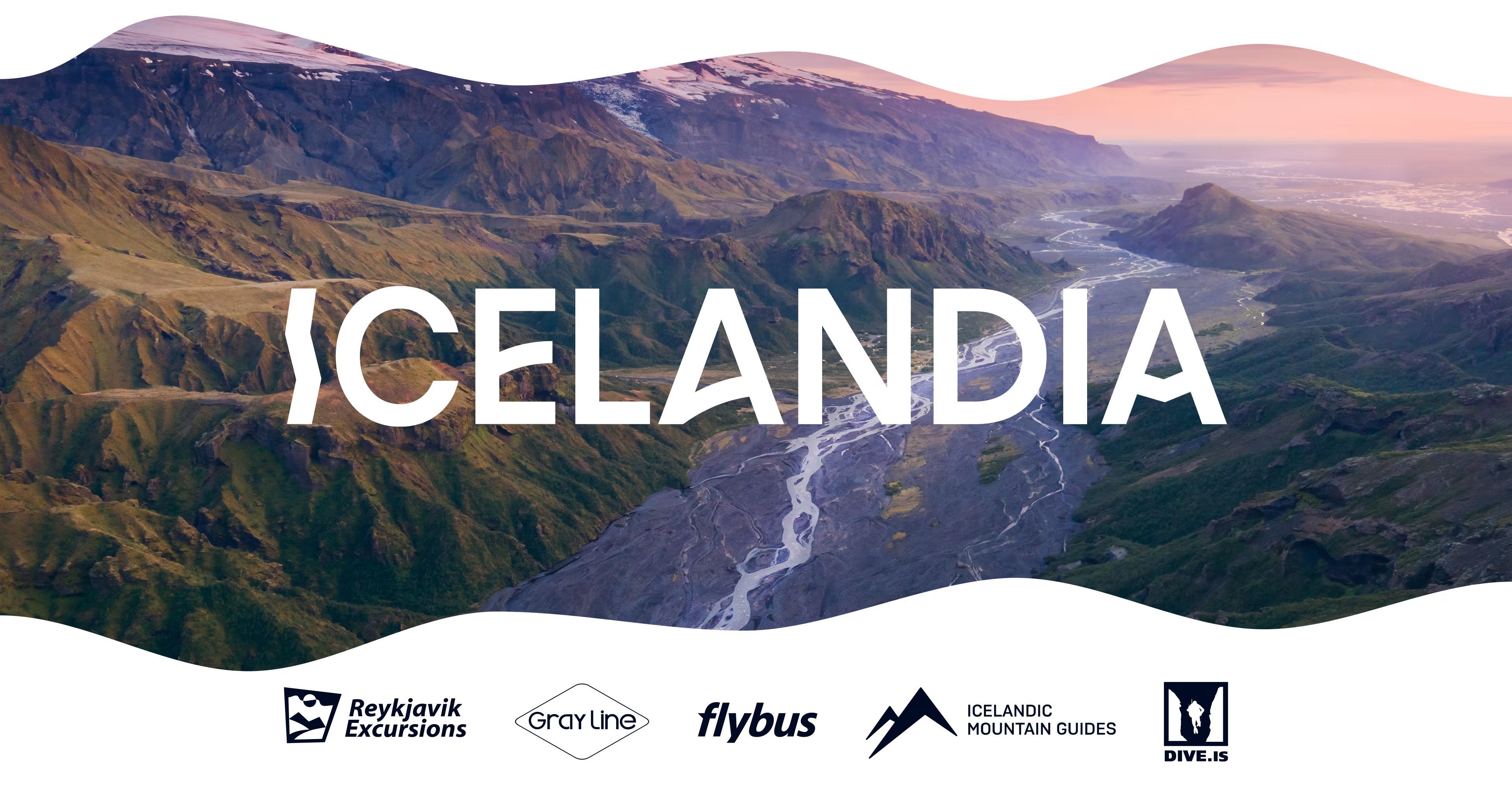 A scenic aerial view of an Icelandic mountain valley at sunset, featuring green ridges, a winding river, and snow-capped peaks in the distance. The word “ICELANDIA” is prominently displayed in bold white letters
