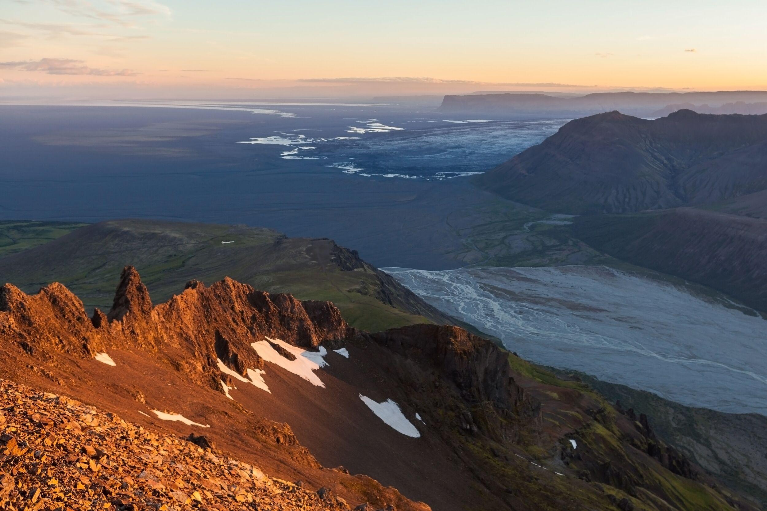 Sharp volcanic ridges of Kristínartindar glowing in golden hour light, with distant glacier views.