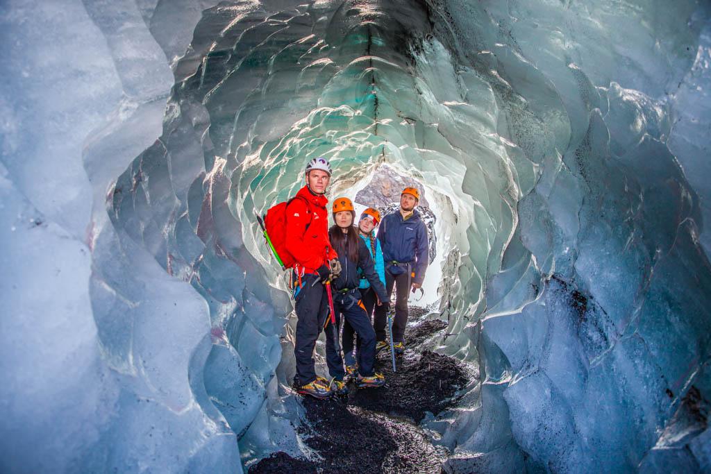 A group of glacier hikers posing for a picture at the entrance of a small ice cave