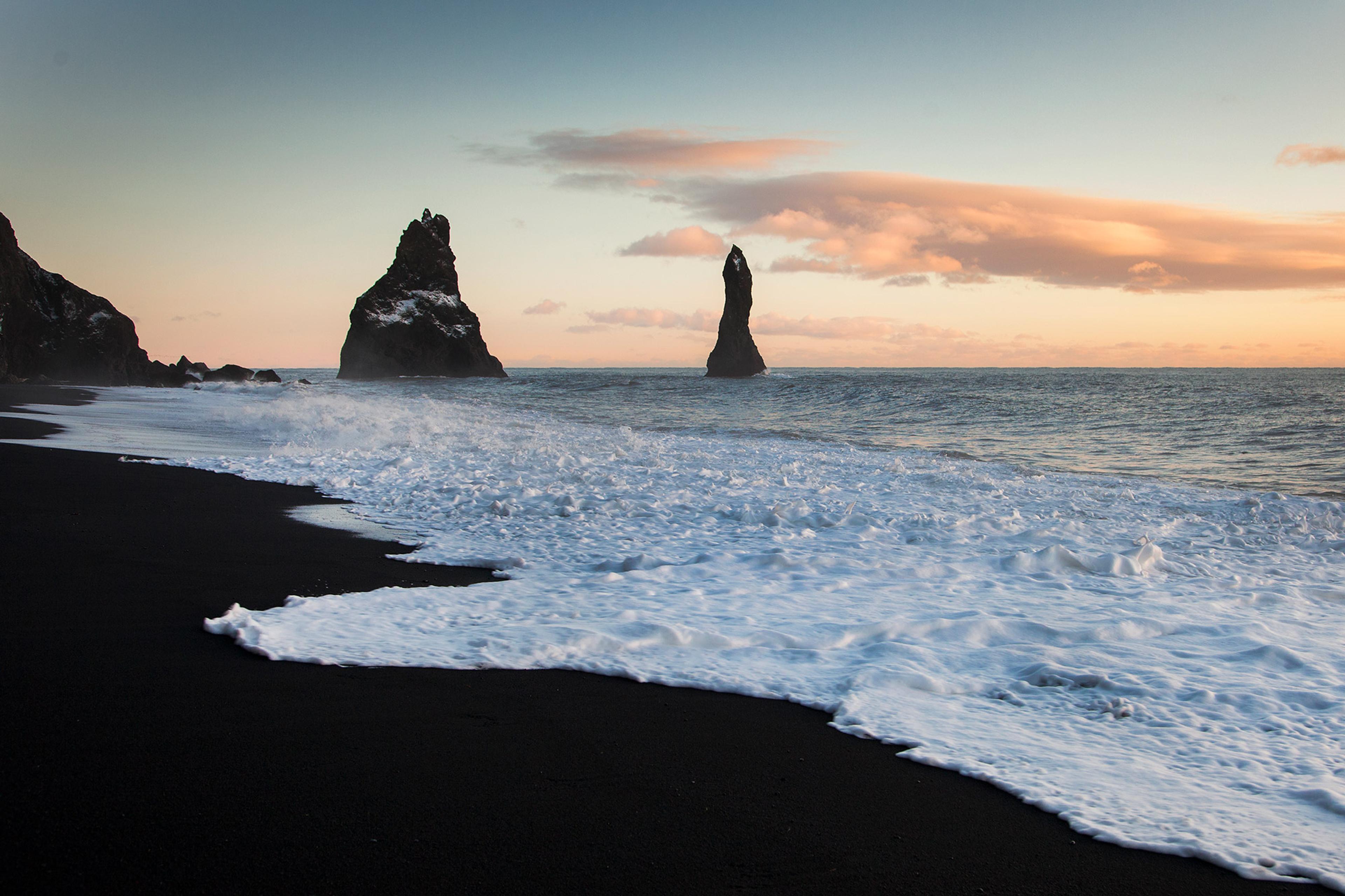 Reynisfjara black sand beach with huge stones in the water at dusk along the south coast of Iceland