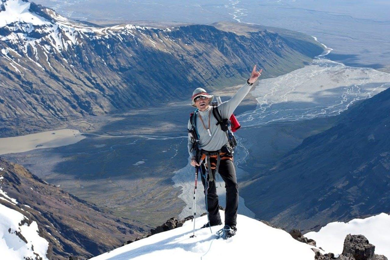 A hiker on the top of the mountain with the river and mountains in the back on a tour with Icelandic Mountain Guides