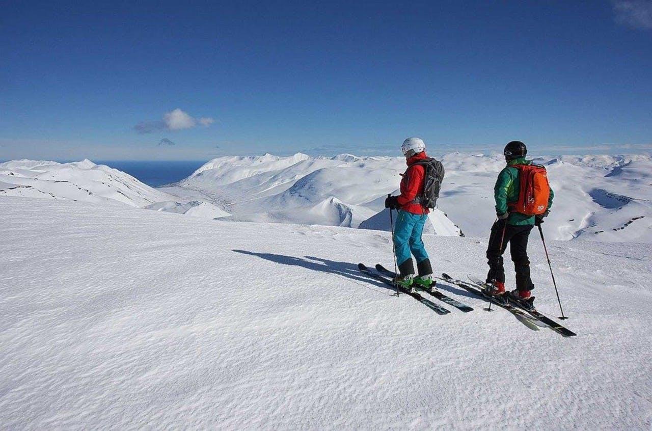 A couple skiing on Hlíðarfjall ski area on a sunny day under the blue sky
