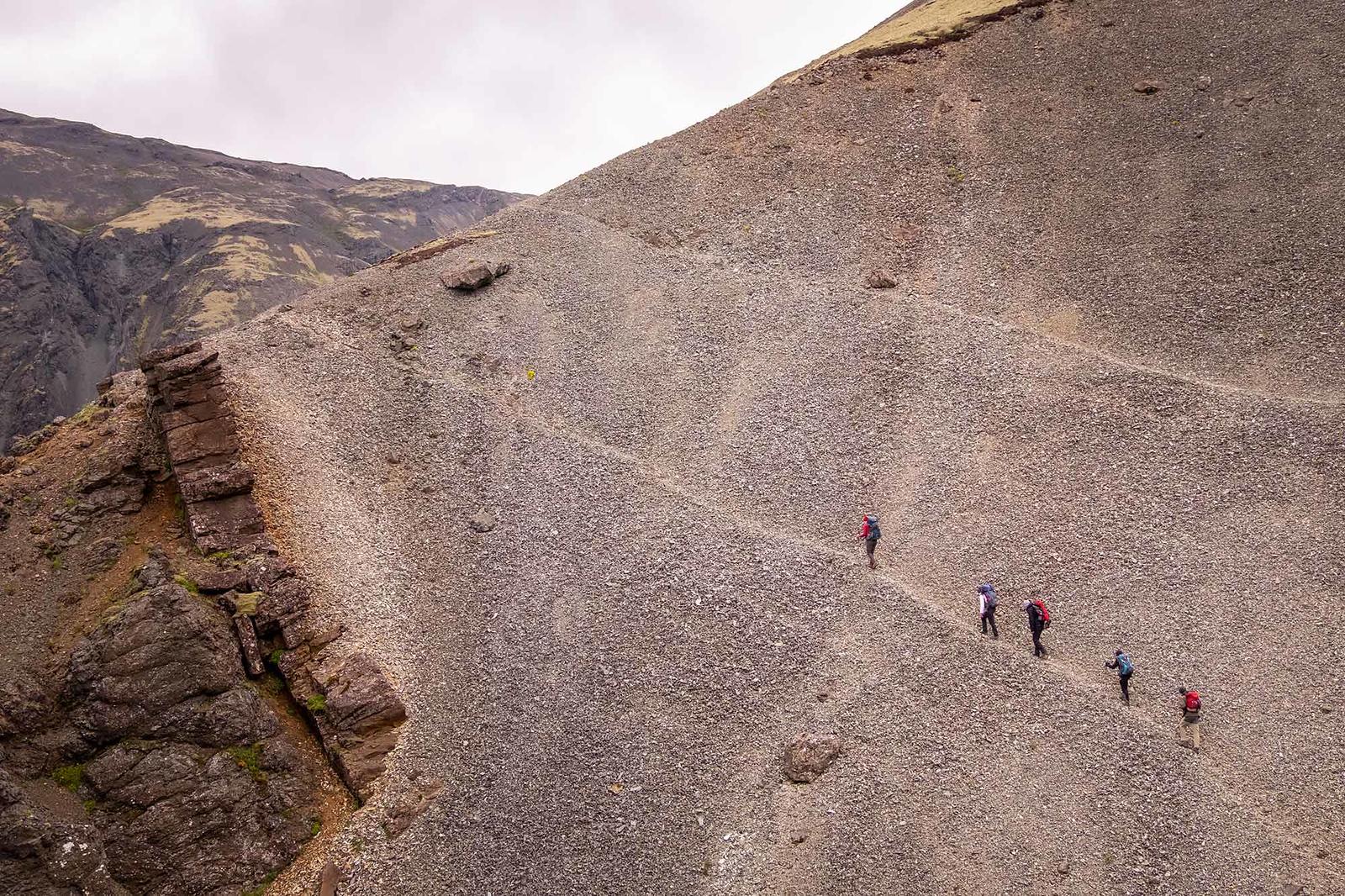 Backpackers walking up a narrow trail in a rock scree in Lonsoraefi area
