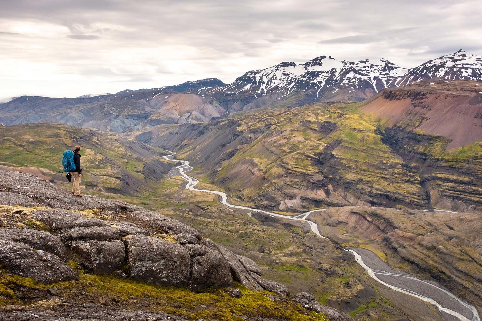 A hiker looking at a stunning landscape where a river runs through the mountains