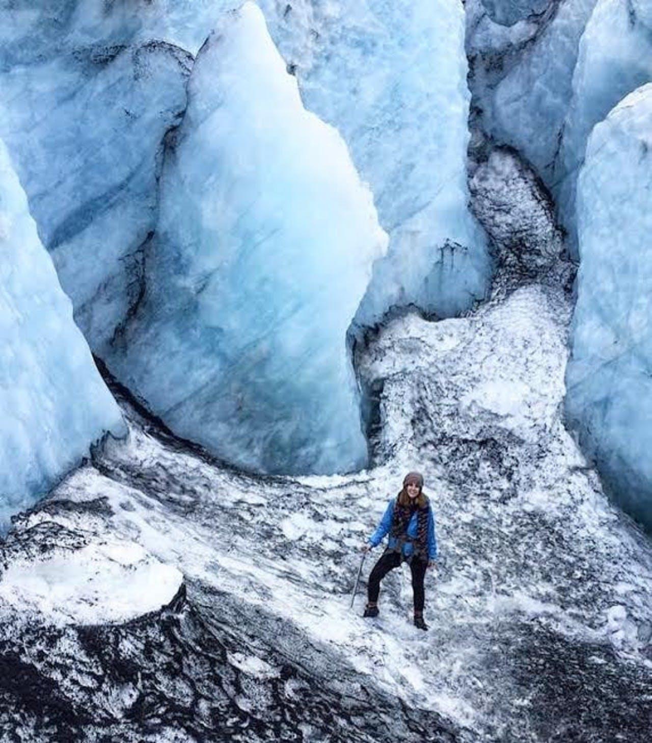 A woman wearing a blue coat surrounded by blue ice