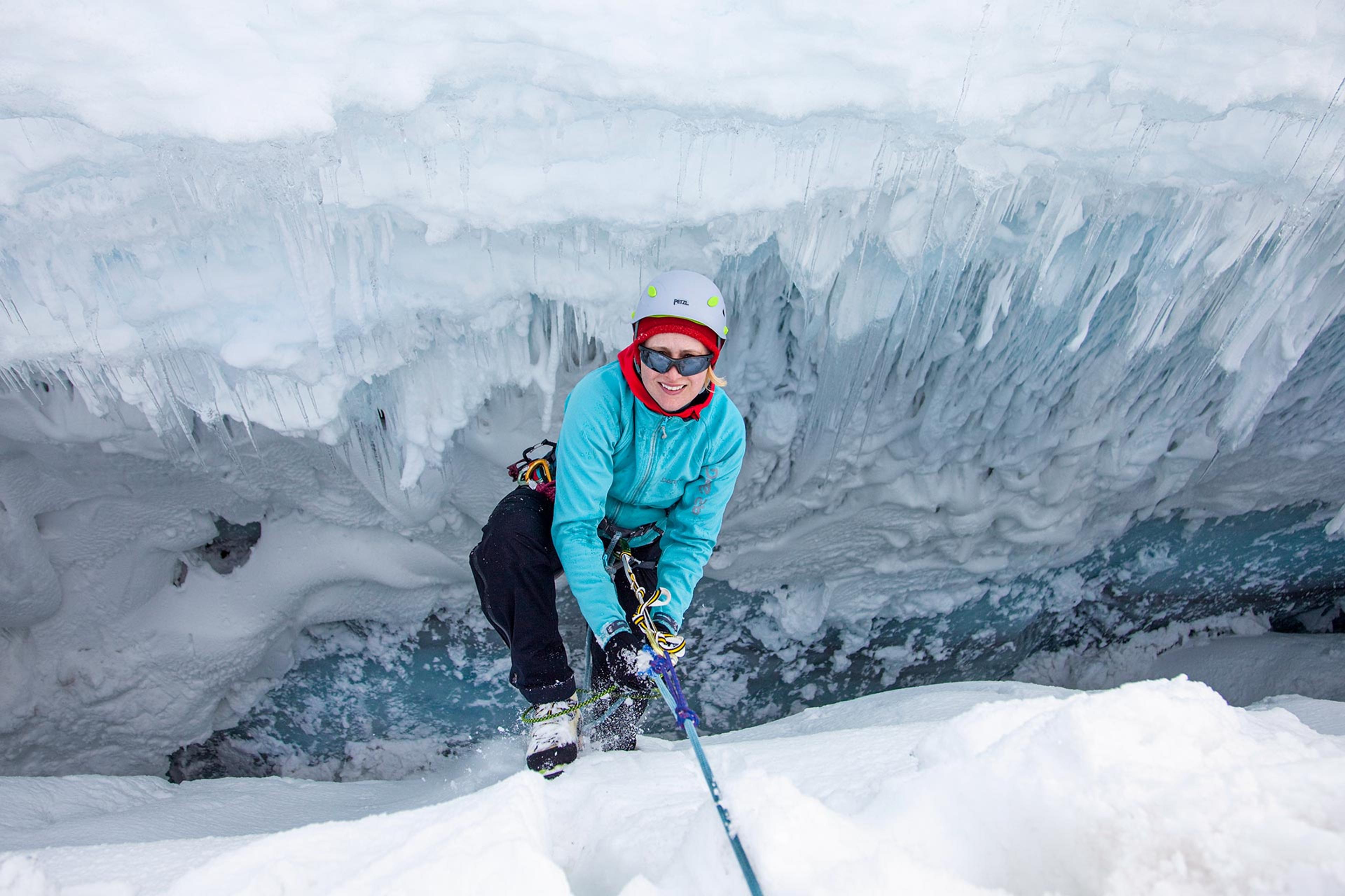 A woman climbing out of a crevasse during glacier training