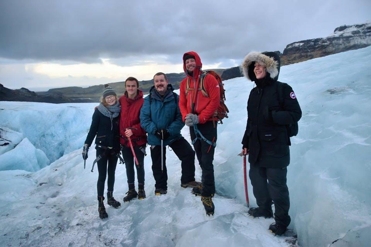 Four happy people with ice hiking gear standing on a glacier
