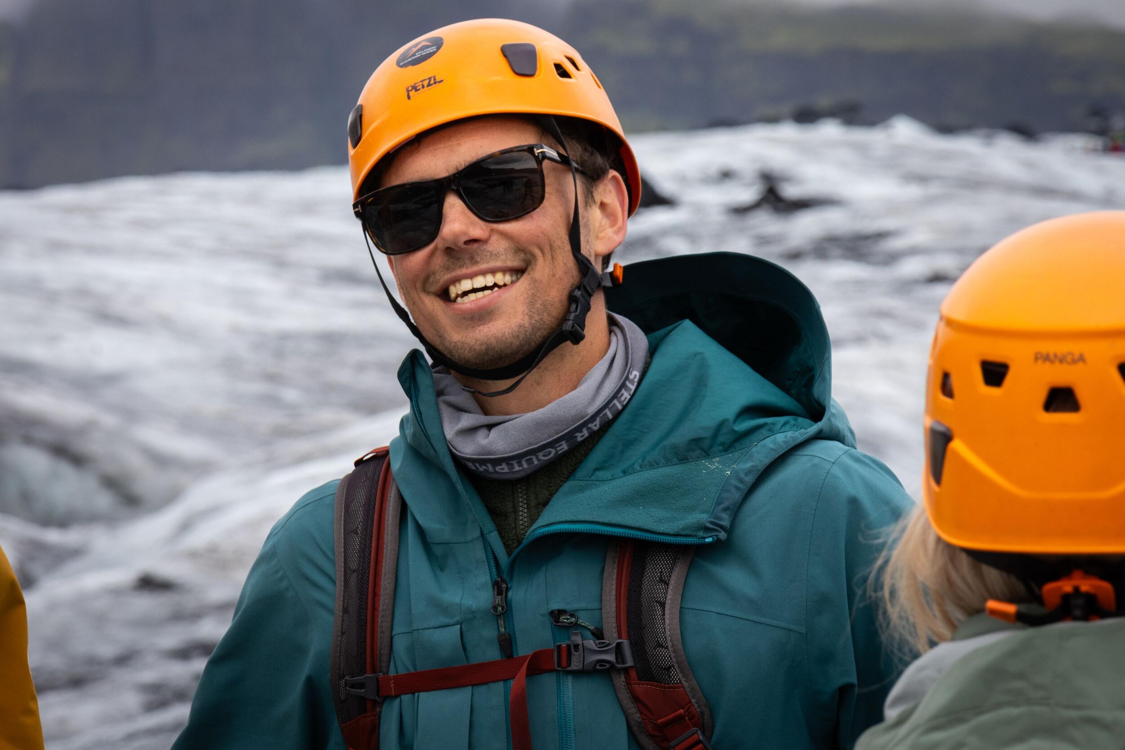man with a helmet and sunglasses happy on a glacier