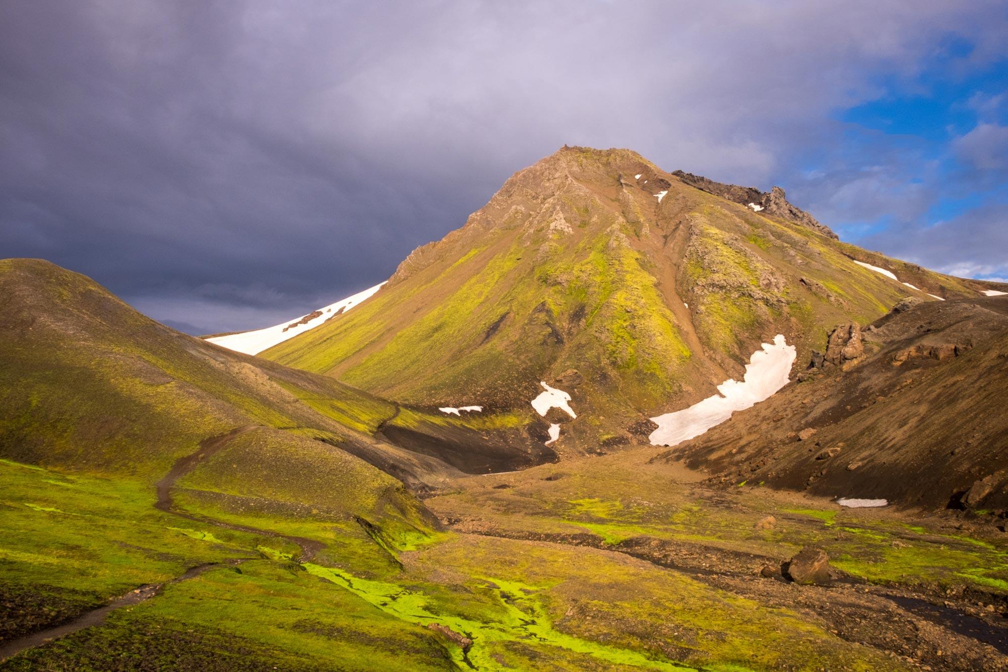 A green well grown mountain lit up by the sun