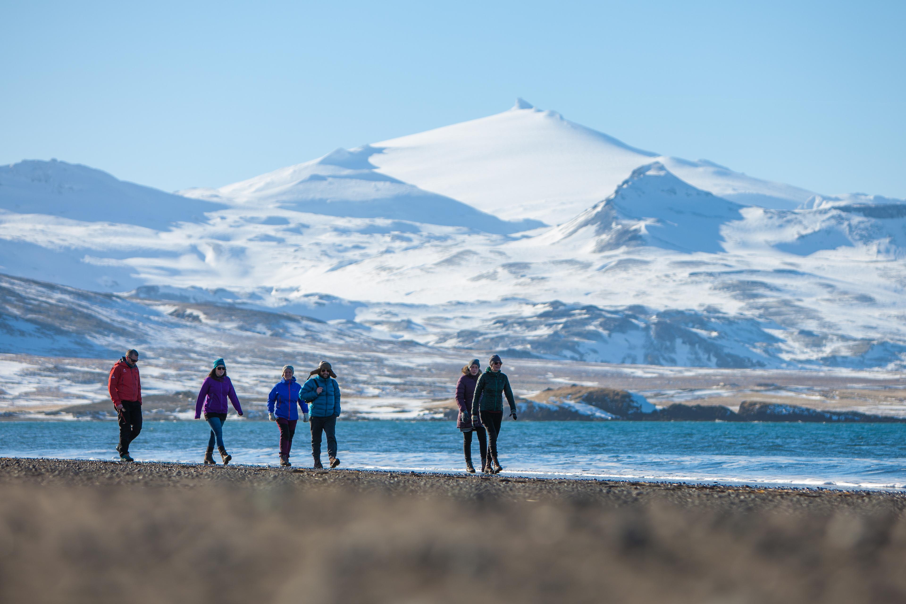 People walking on the beach with Sneafellsjökull glacier in the background