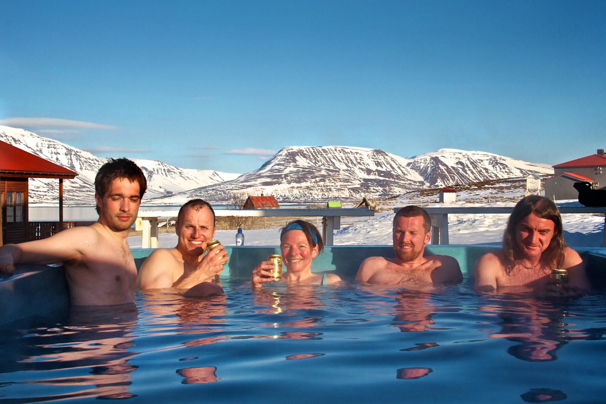 People relaxing in a hot tub with snowy mountains behind them in the North of Iceland