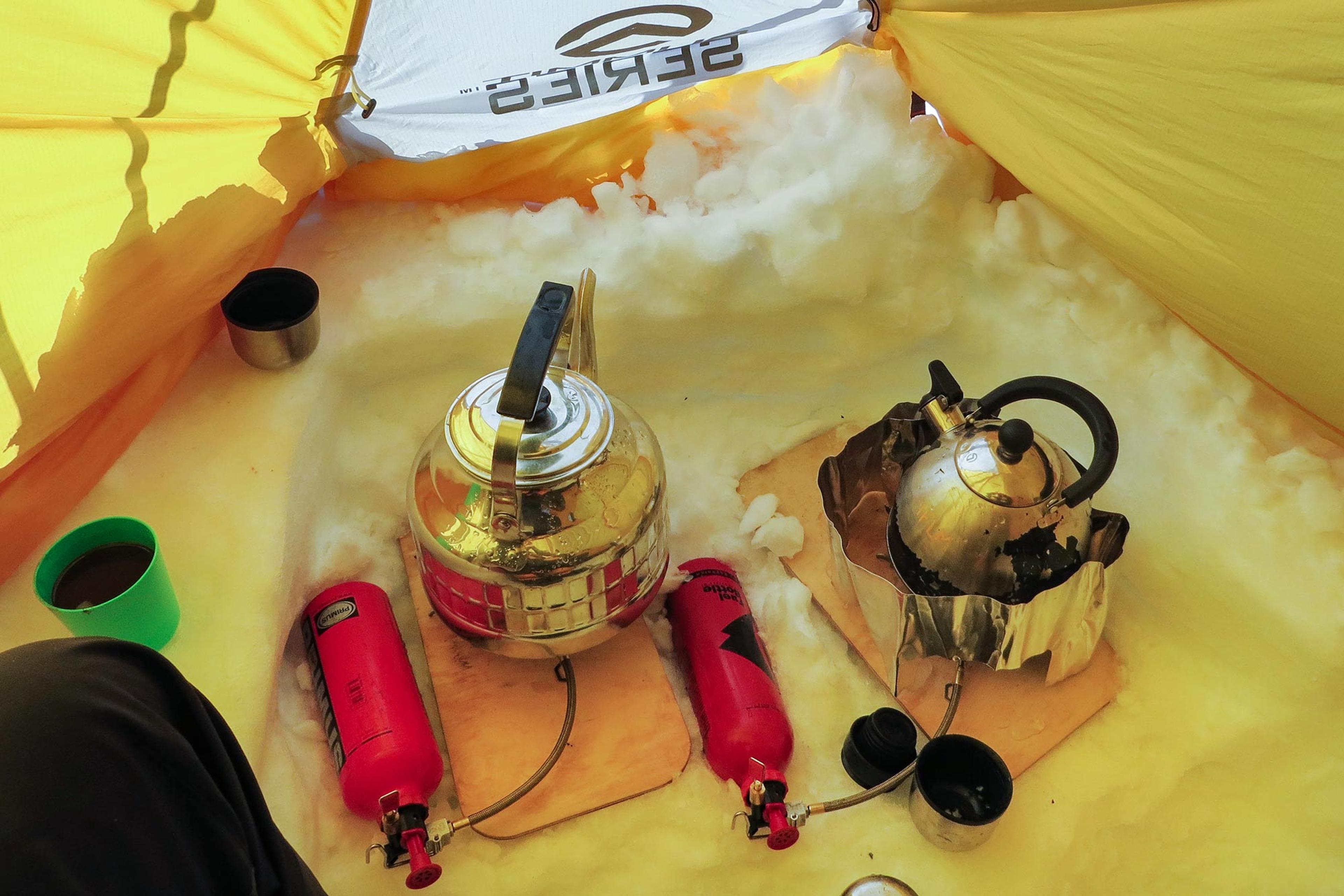 Two kettles brewing water inside a tent on the Greenland glacier
