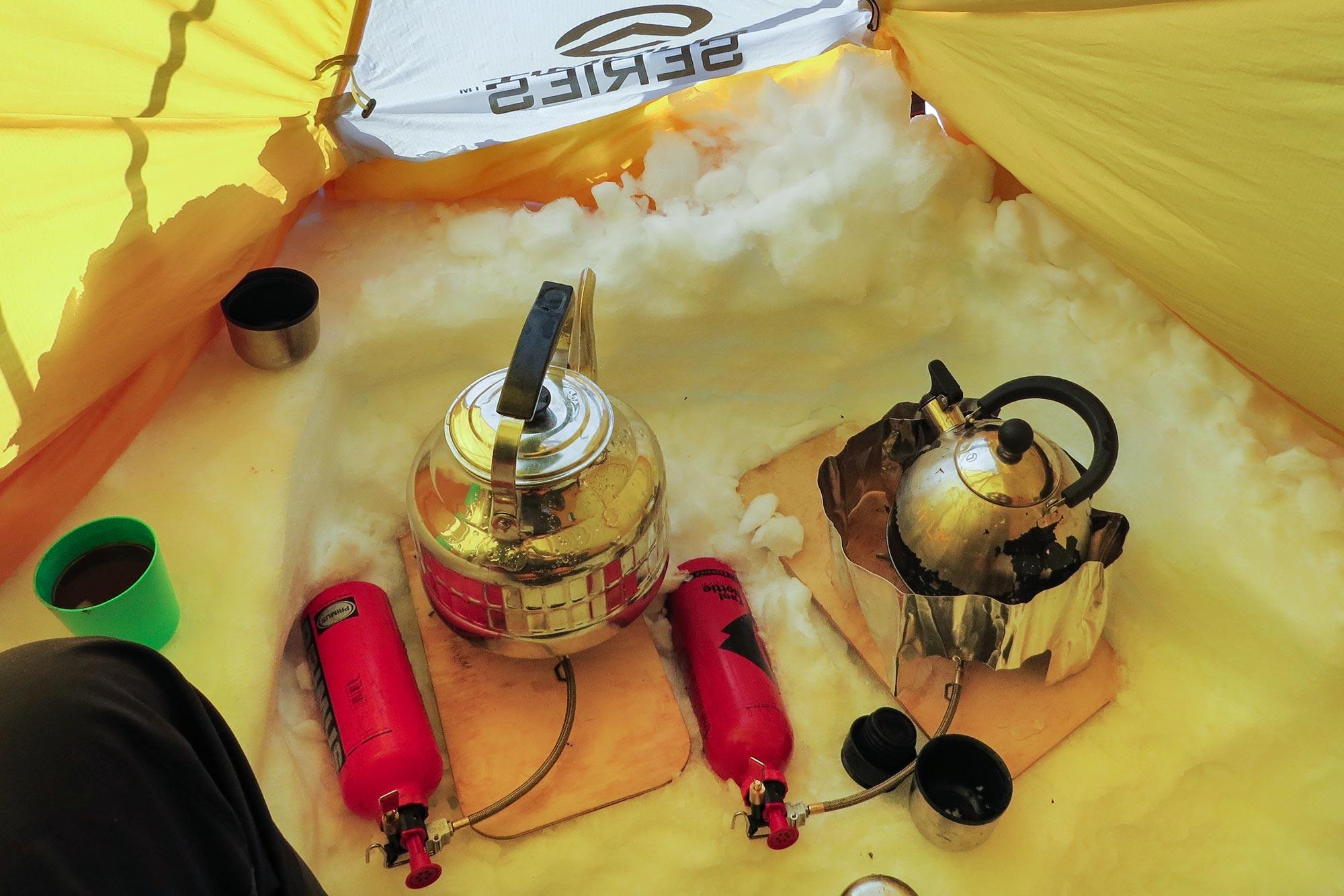 Two kettles brewing water inside a tent on the Greenland glacier