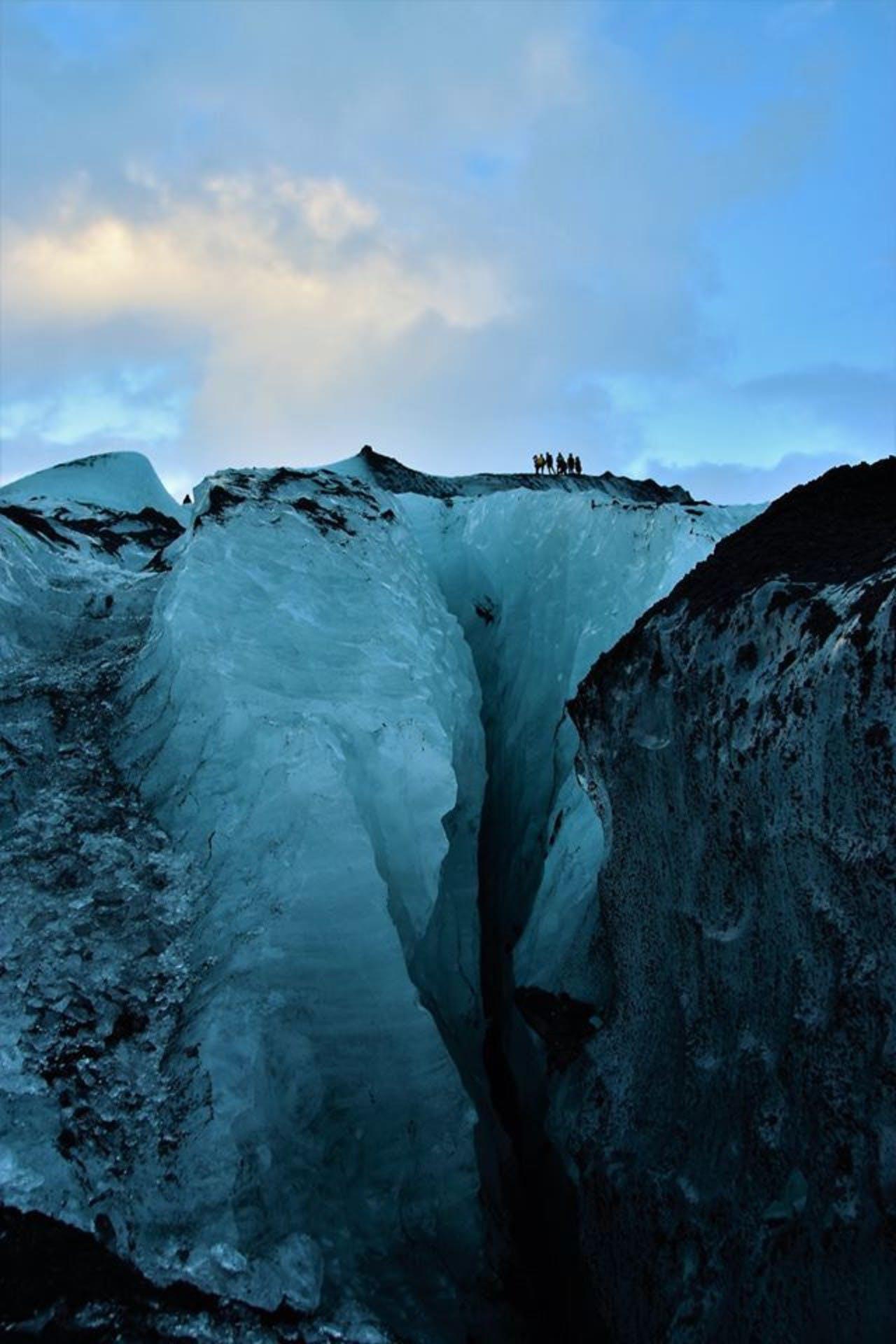 big blue glacier with people on top