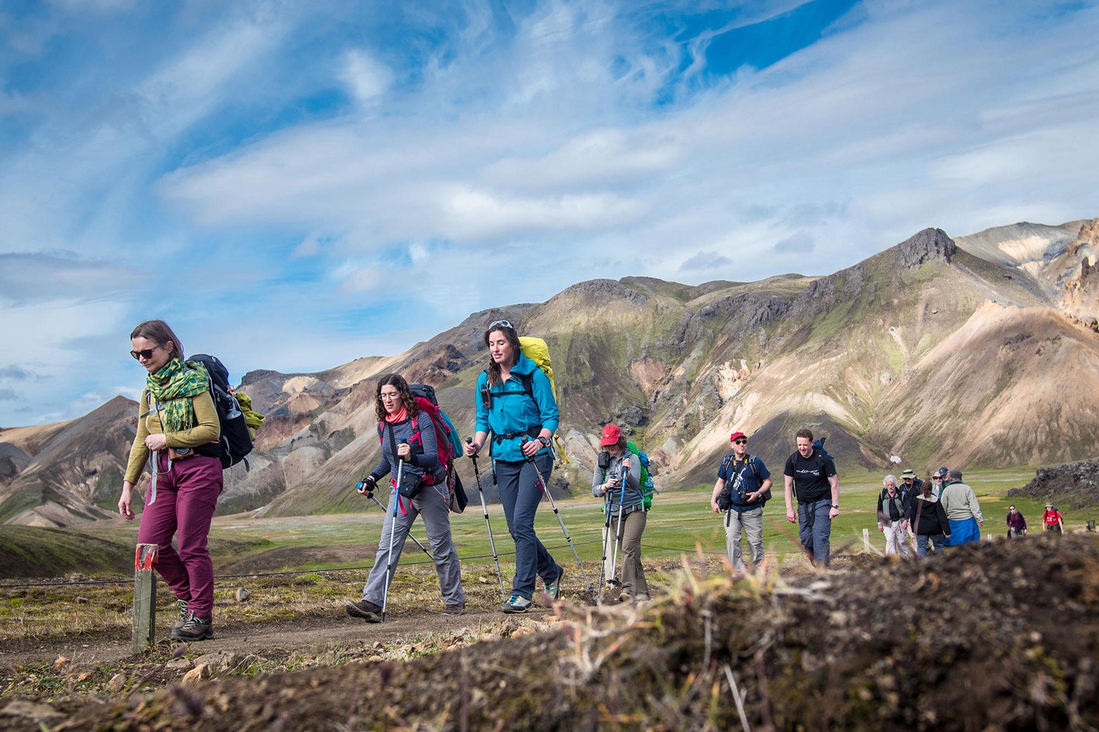 People hiking through a nature valley in Iceland with the blue sky and colorful mountains