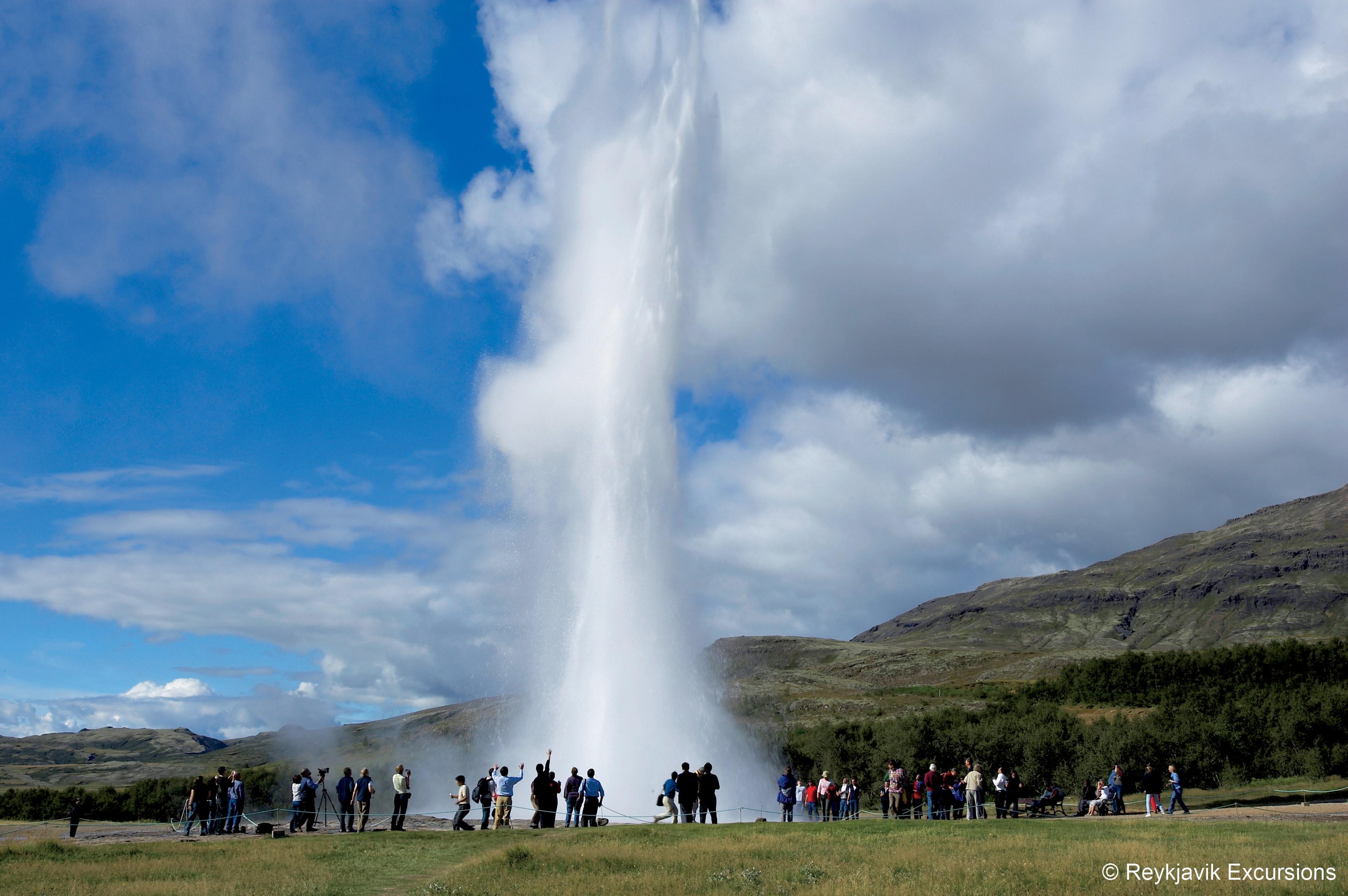 Strokkur geyser erupting in front of a crowd