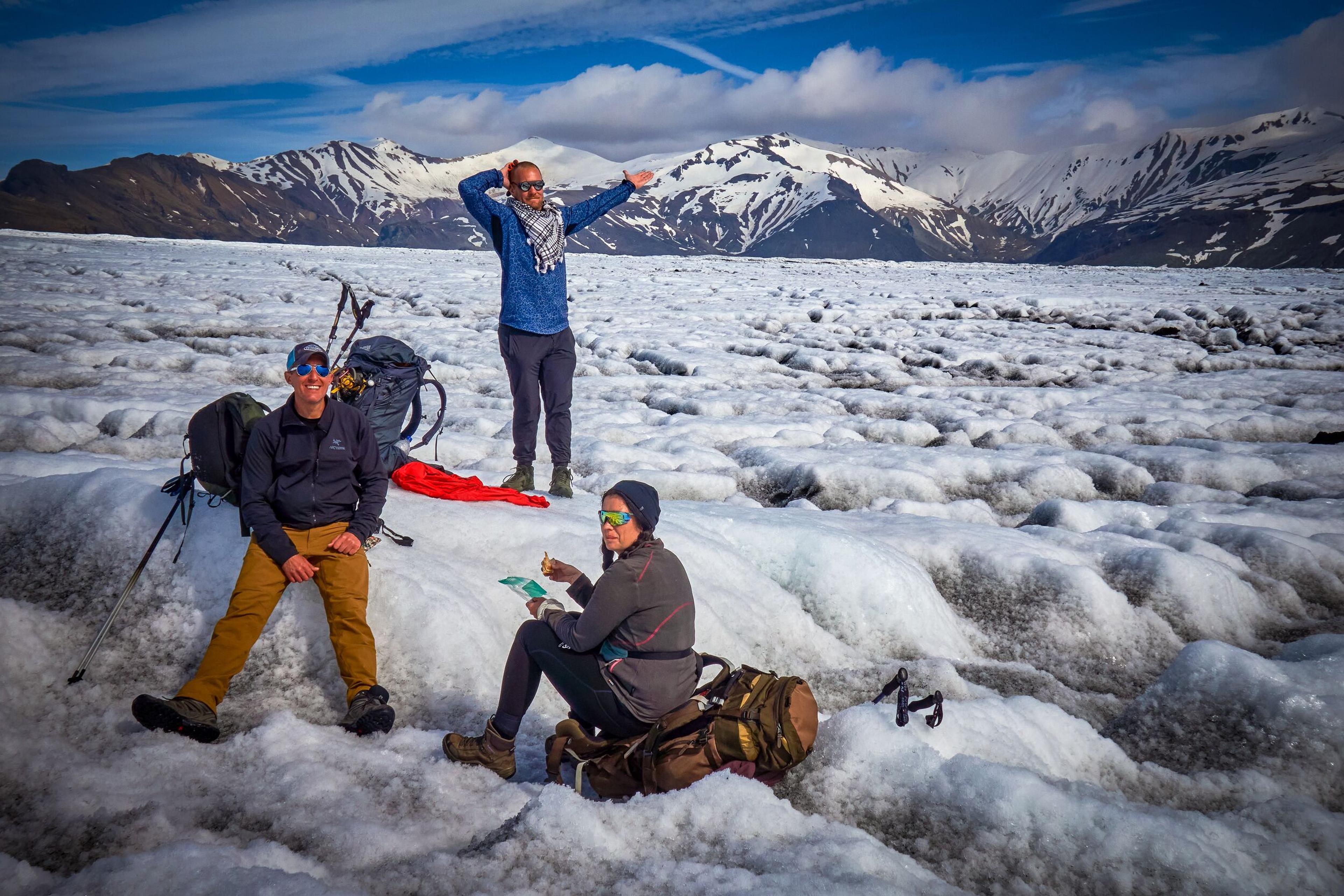 Three hikers taking a break on a glacier on a sunny day