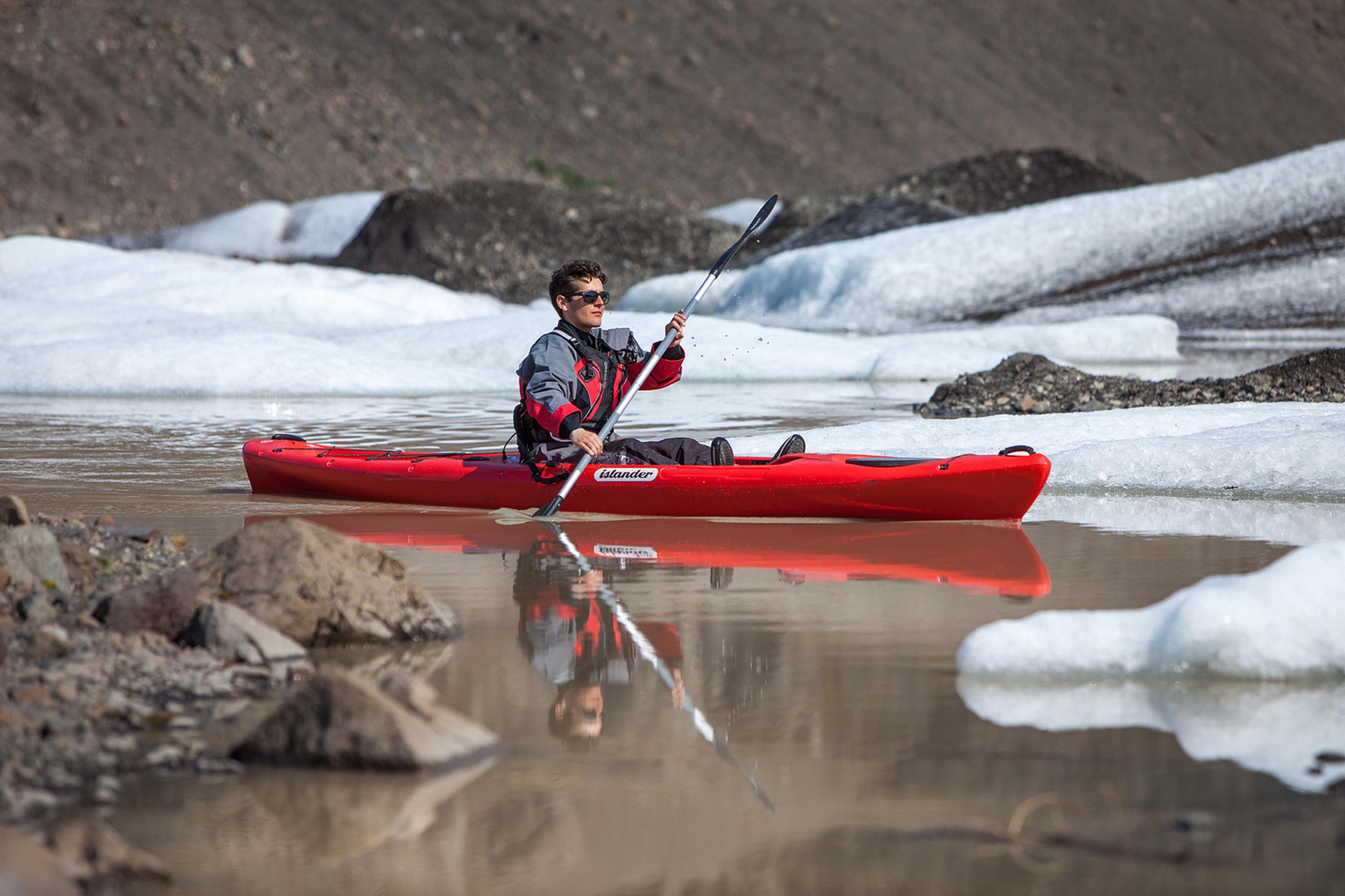 a kayak guide on a perfectly calm water with a beautiful reflection and ice all around