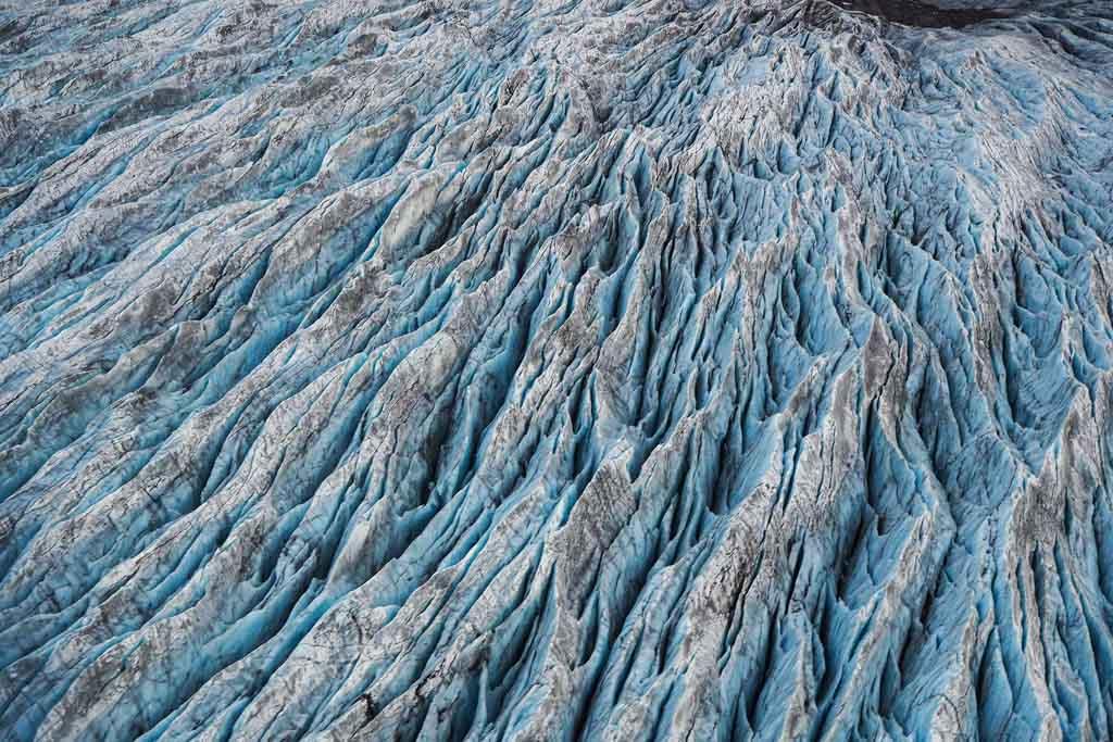 An aerial view of a glacier. Rugged terrain and deep crevasses