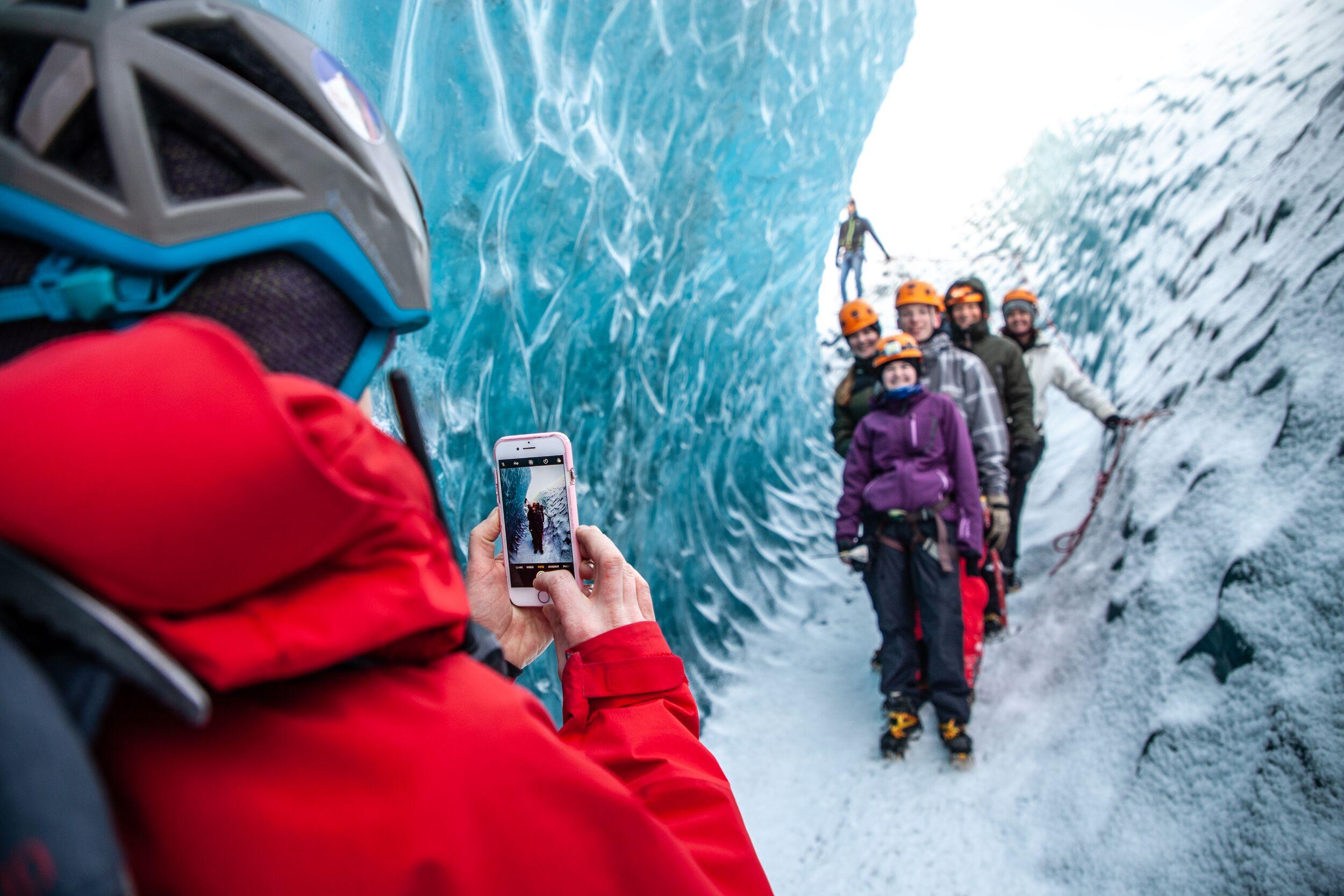 Person taking photos of a group on a glacier